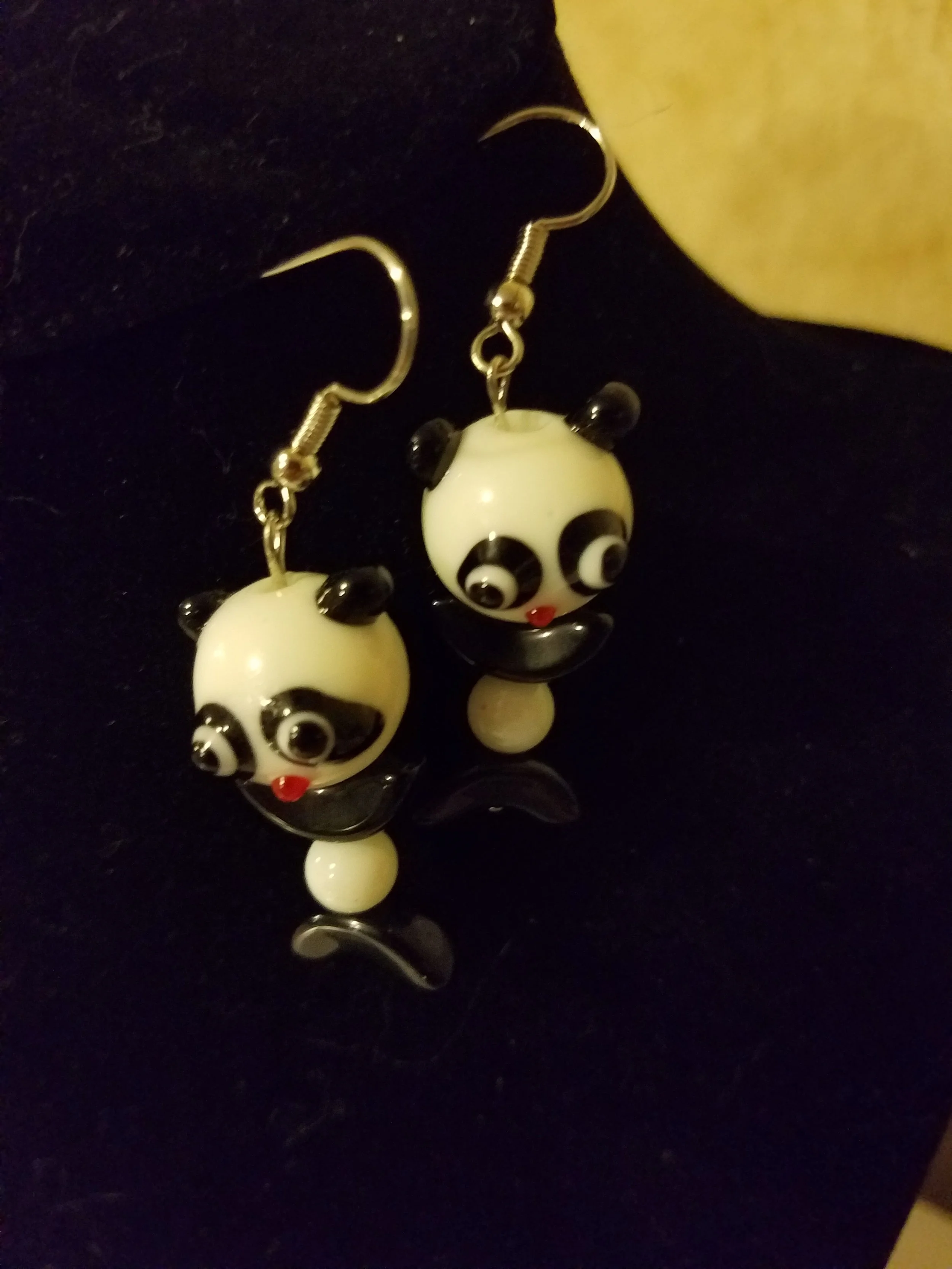 Pair of panda-themed dangle earrings with white and black panda faces, red tongue, and black ears, hanging on silver hooks.