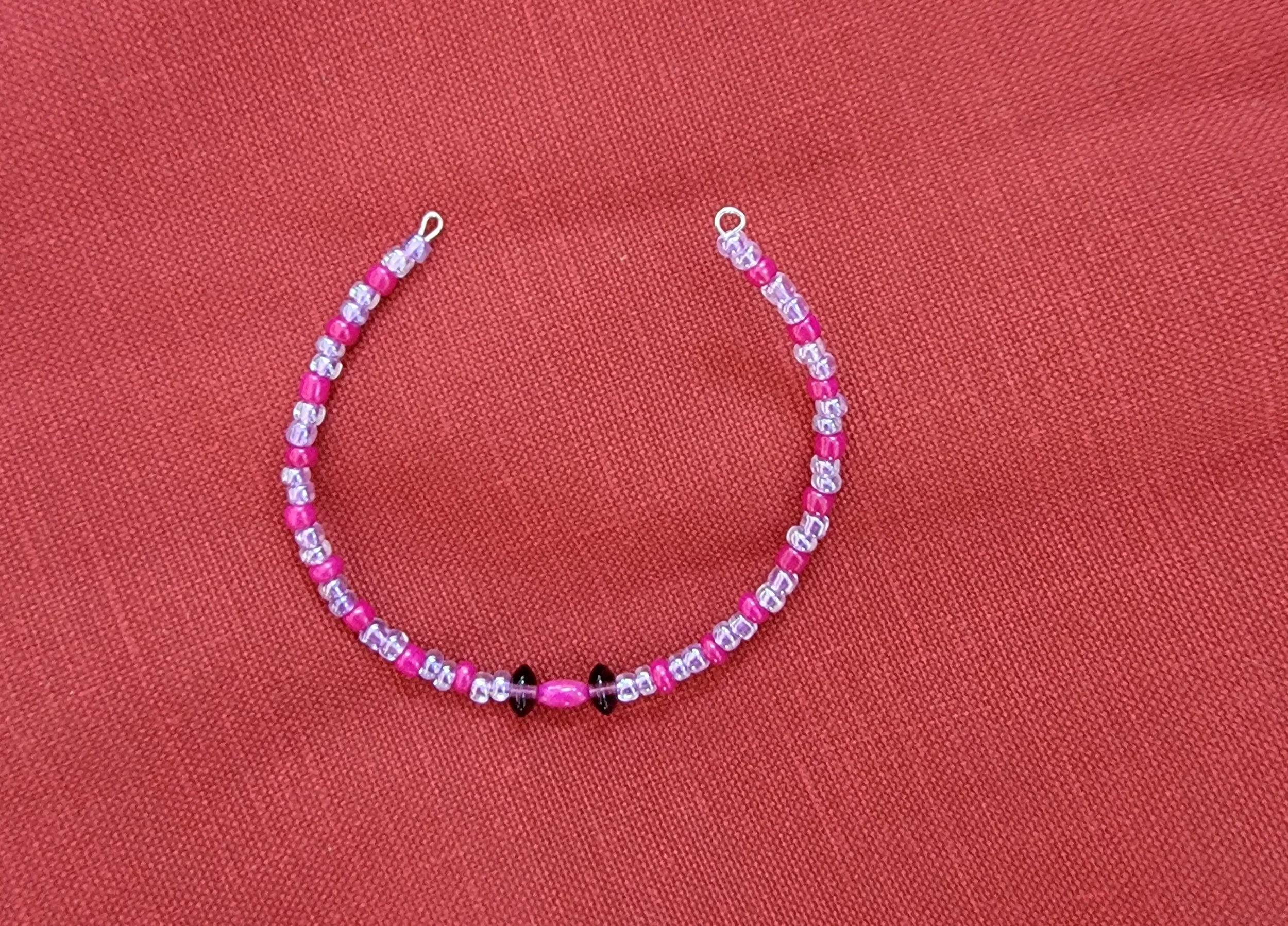 Pink and clear beaded bracelet on red fabric background.