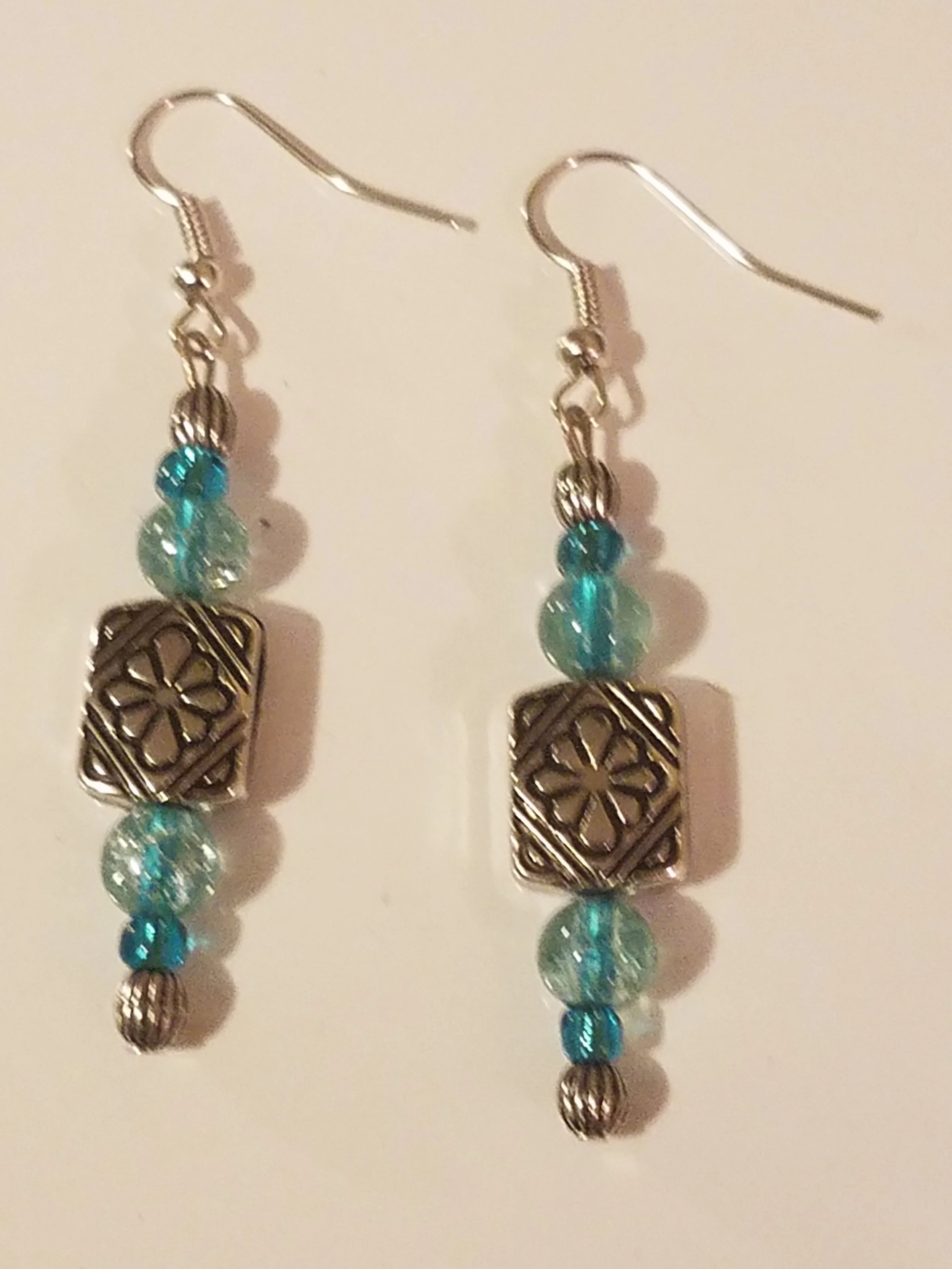 Silver earrings with blue beads and decorative square silver charms.