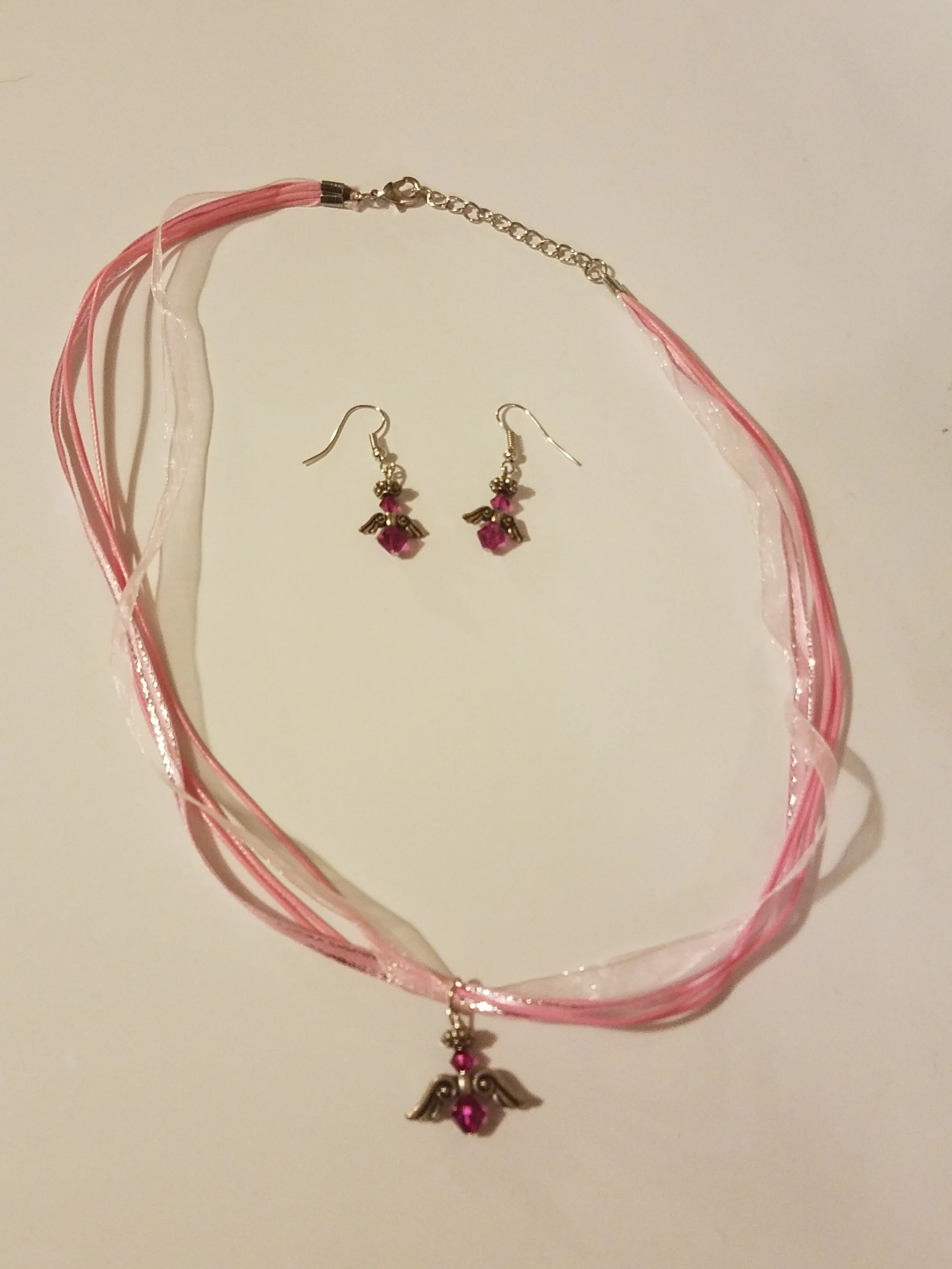 Pink and white ribbon choker with a winged heart pendant, matching winged heart earrings with pink stones.