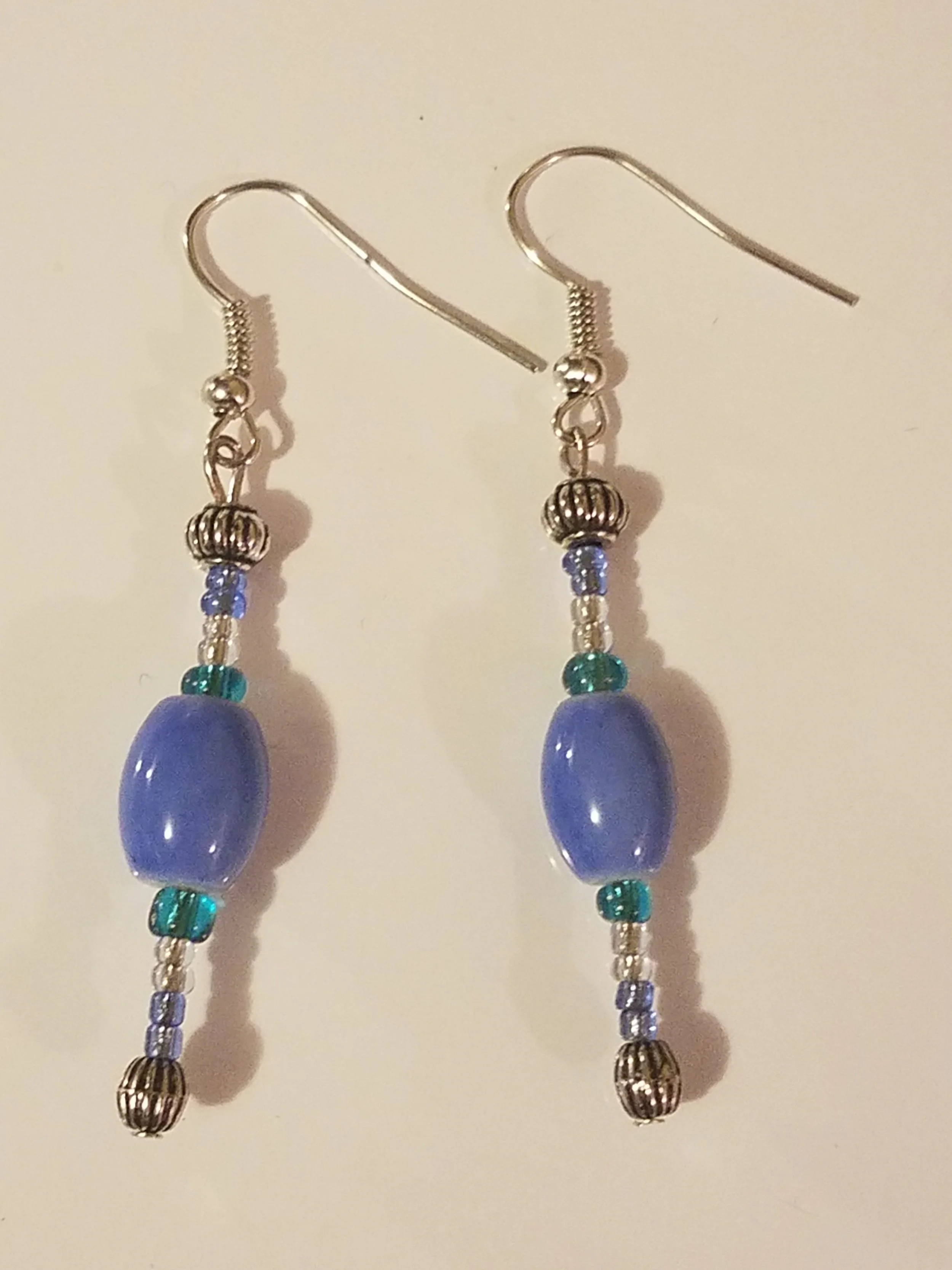 Beaded dangle earrings with blue, green, purple, and silver beads on silver hooks.