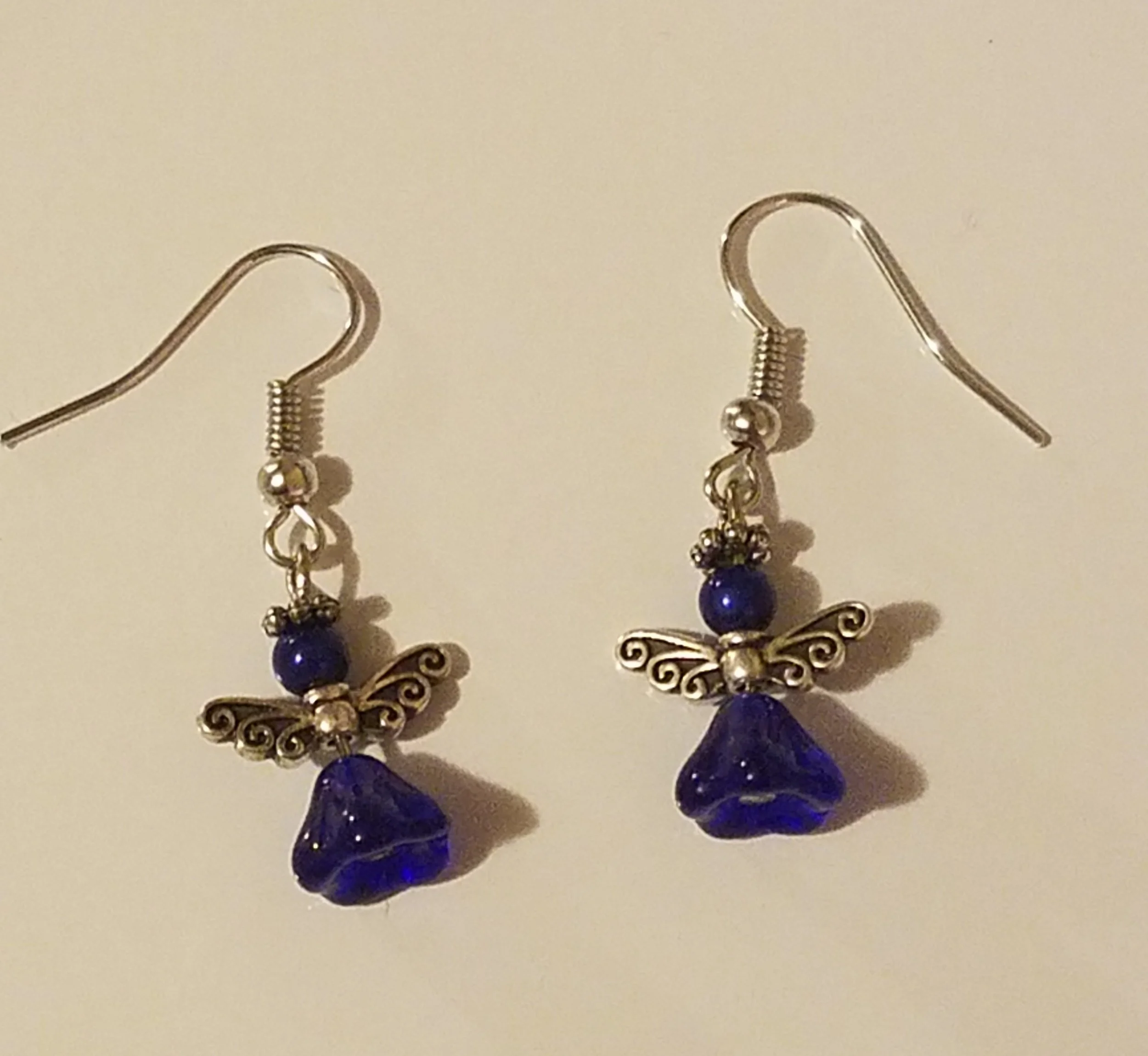 Silver earrings with blue beads and butterfly charms on a white background.