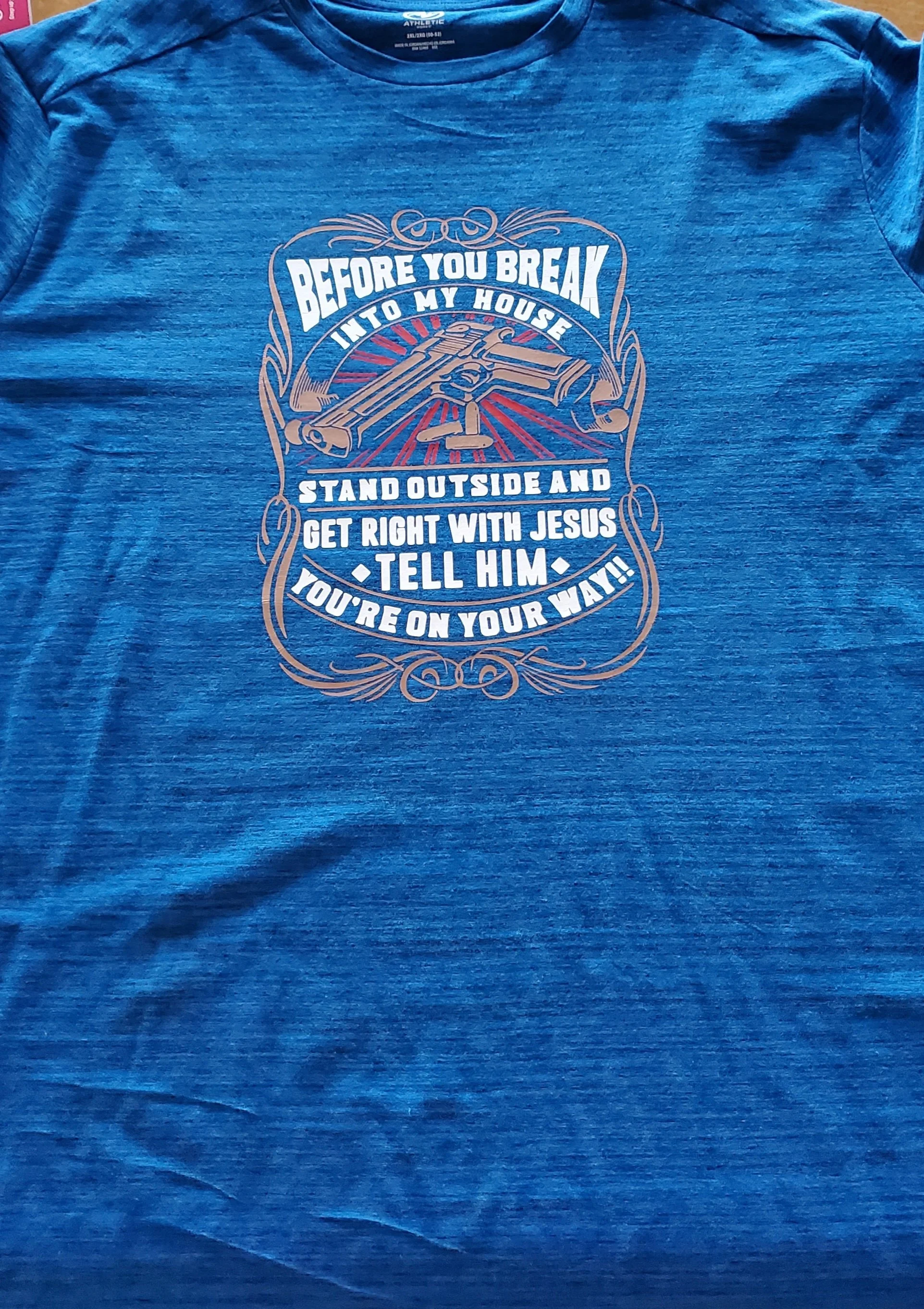 Blue T-shirt with a graphic and text that reads, 'Before you break into my house, stand outside and get right with Jesus, tell him, you're on your way!'