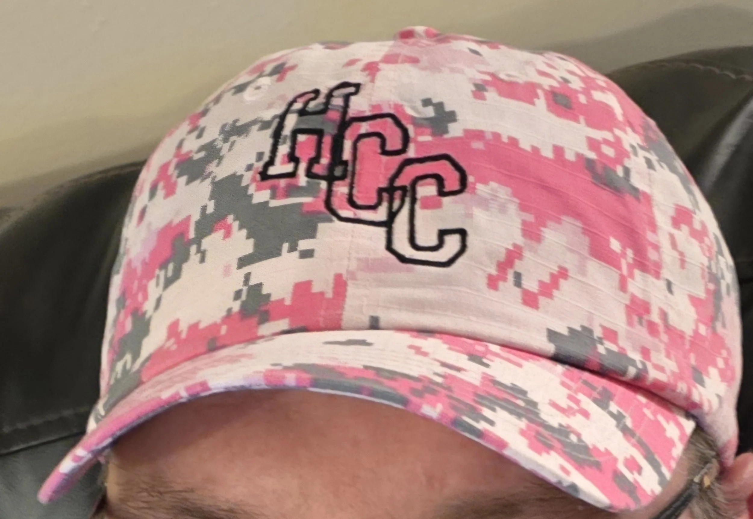 A person wearing a pink, gray, and white camouflage baseball cap with the University of Southern California (USC) logo embroidered on the front.