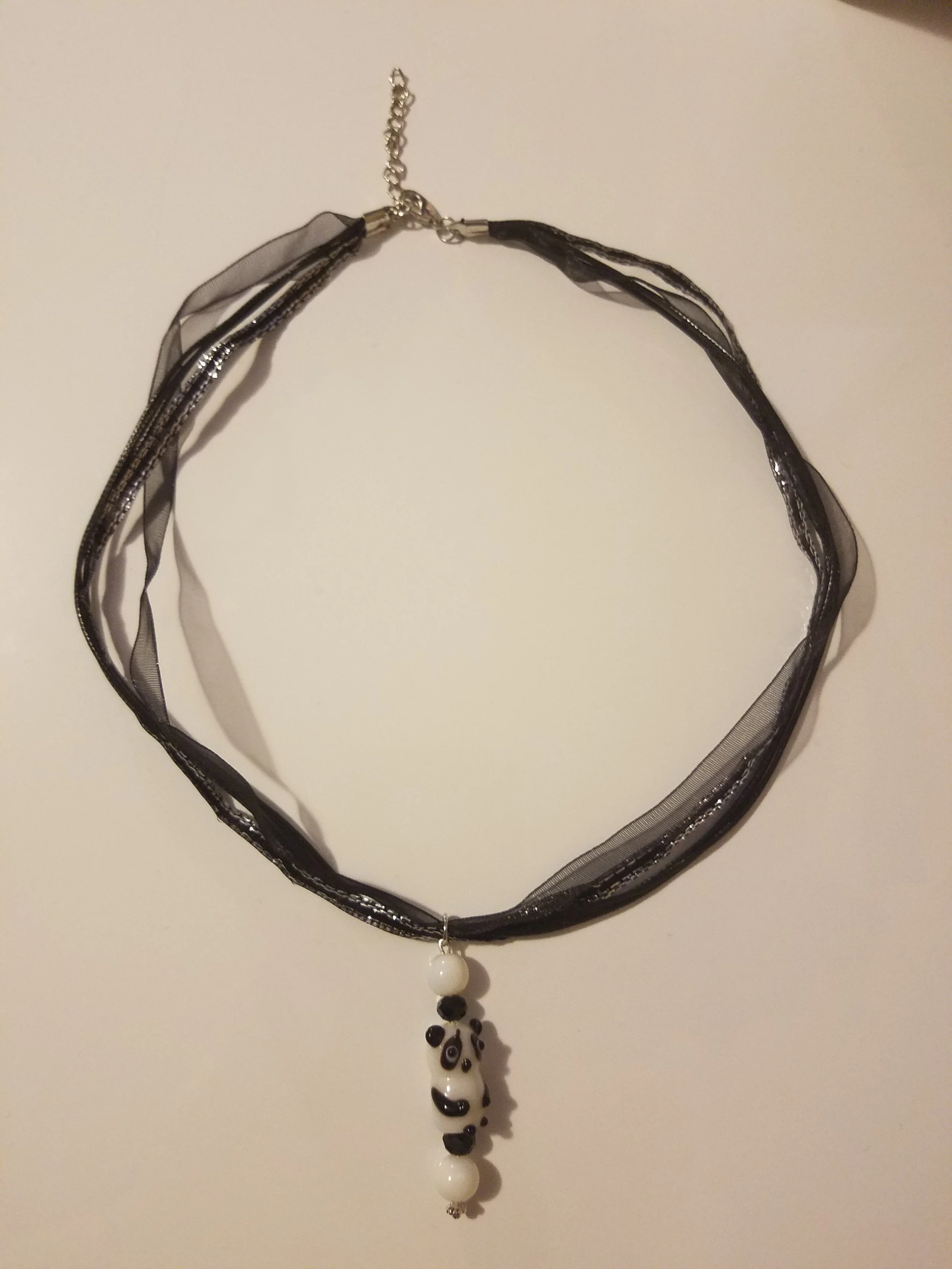 Black and gray fabric choker necklace with panda bear bead pendant on a white background.