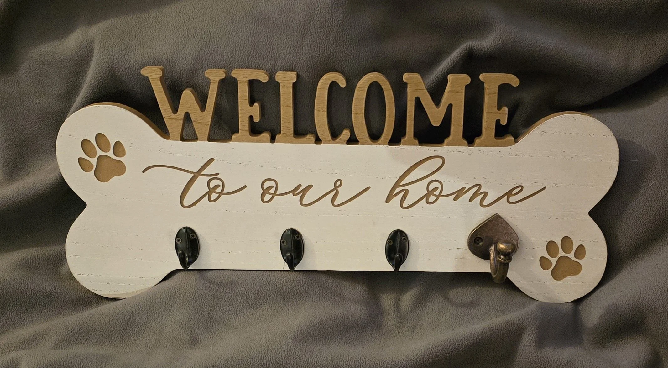 Wooden wall decor with the words "Welcome to our home" and paw print accents, featuring hooks for hanging keys or accessories.