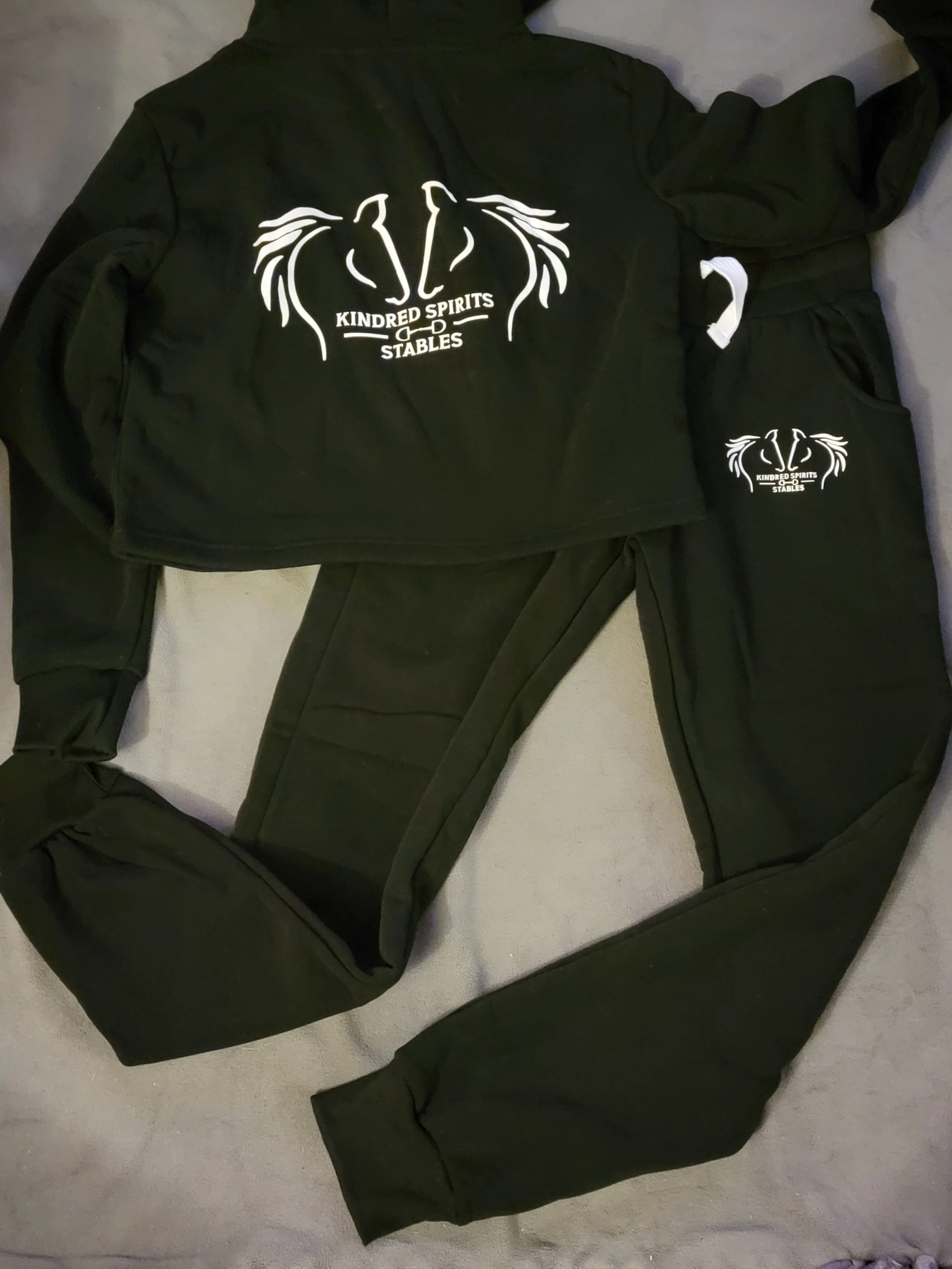 Black sweatshirt and sweatpants with white logo and text reading 'Kindred Spirits Stables'.