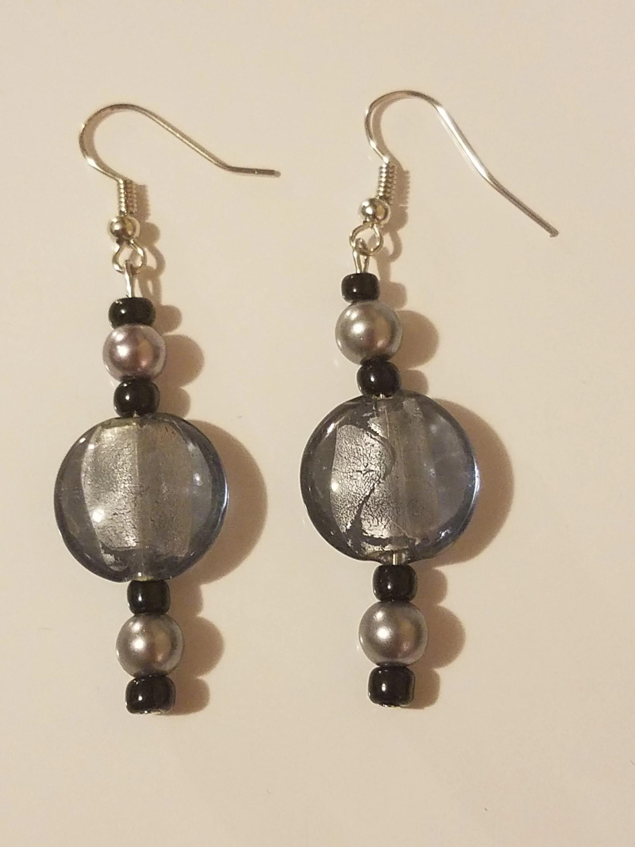 A pair of dangling earrings with black, silver, and clear beads.