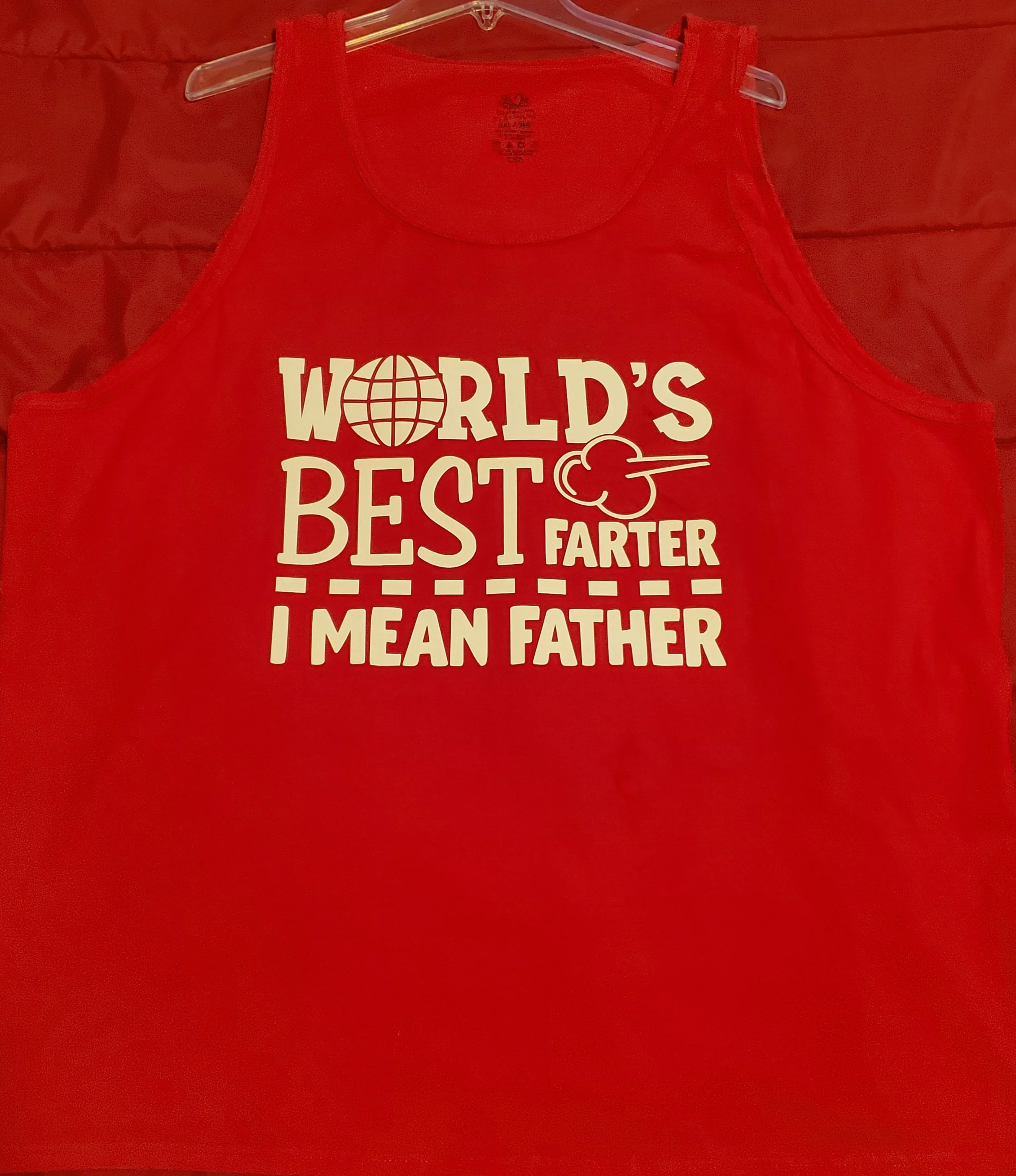 Red sleeveless shirt with white text that says, "World's Best Farter I Mean Father," with a globe icon replacing the letter "O" in "World" and a fart cloud graphic next to the word "Farter."