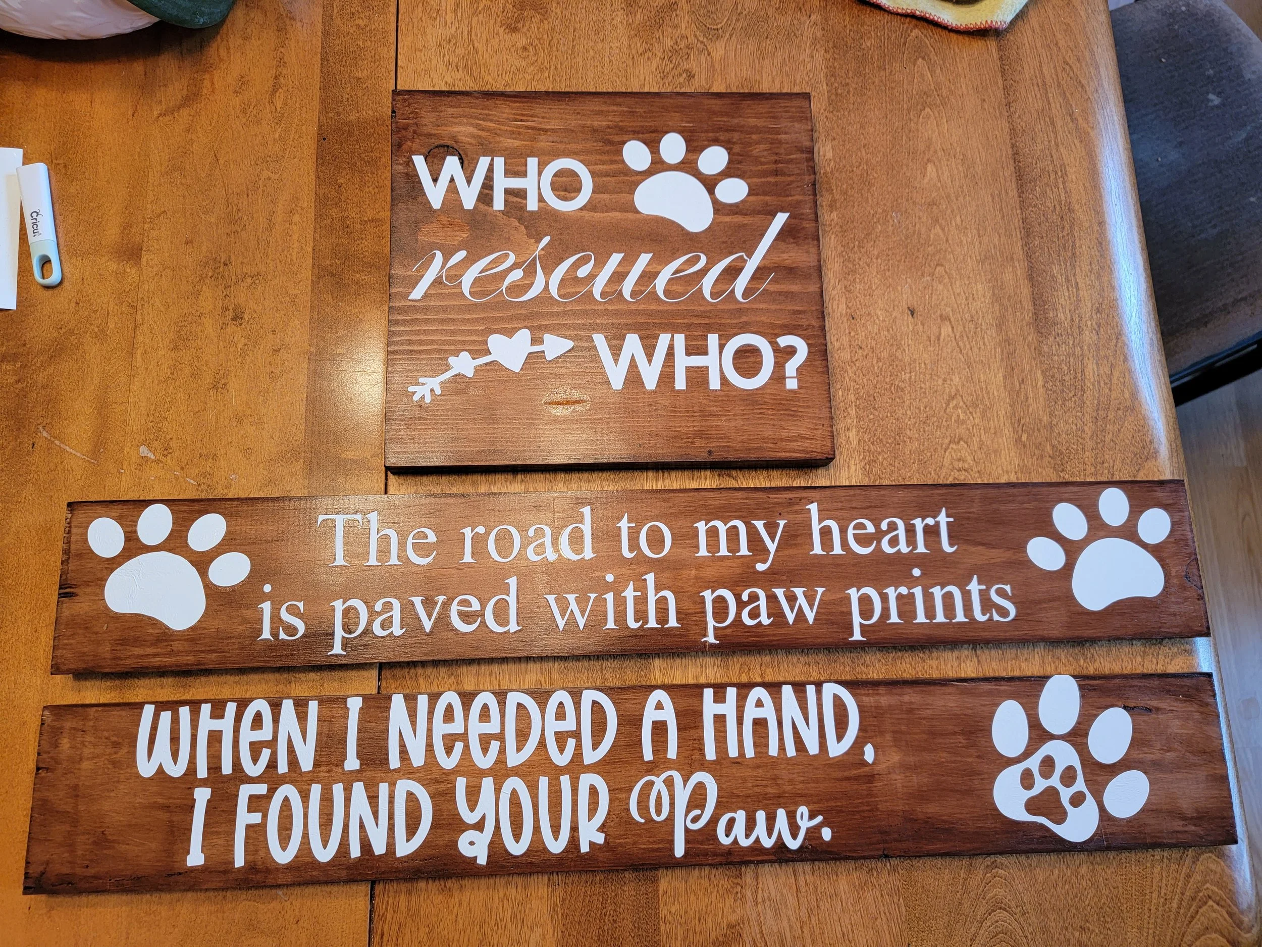 Three wooden plaques with paw print and heart designs, featuring quotes about rescued dogs and paw prints.