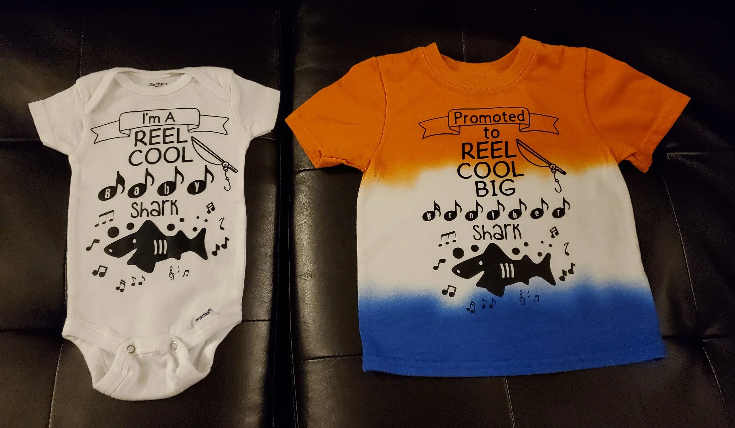 Two children's T-shirts, one white and one tie-dye with orange, white, and blue, featuring a shark and musical notes with the text about reels and fishing.