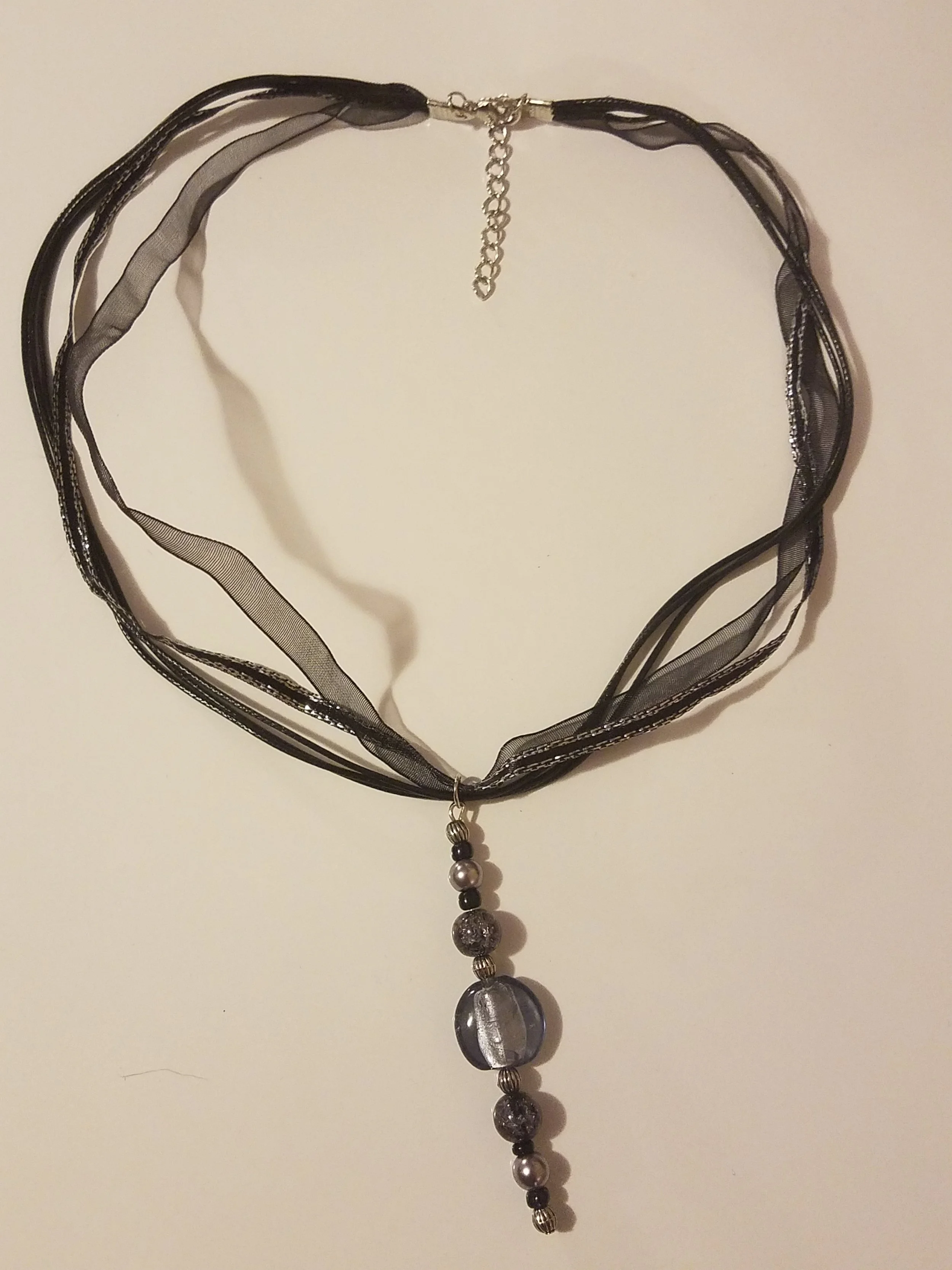 Black and gray beaded necklace with a pendant and a black ribbon choker.