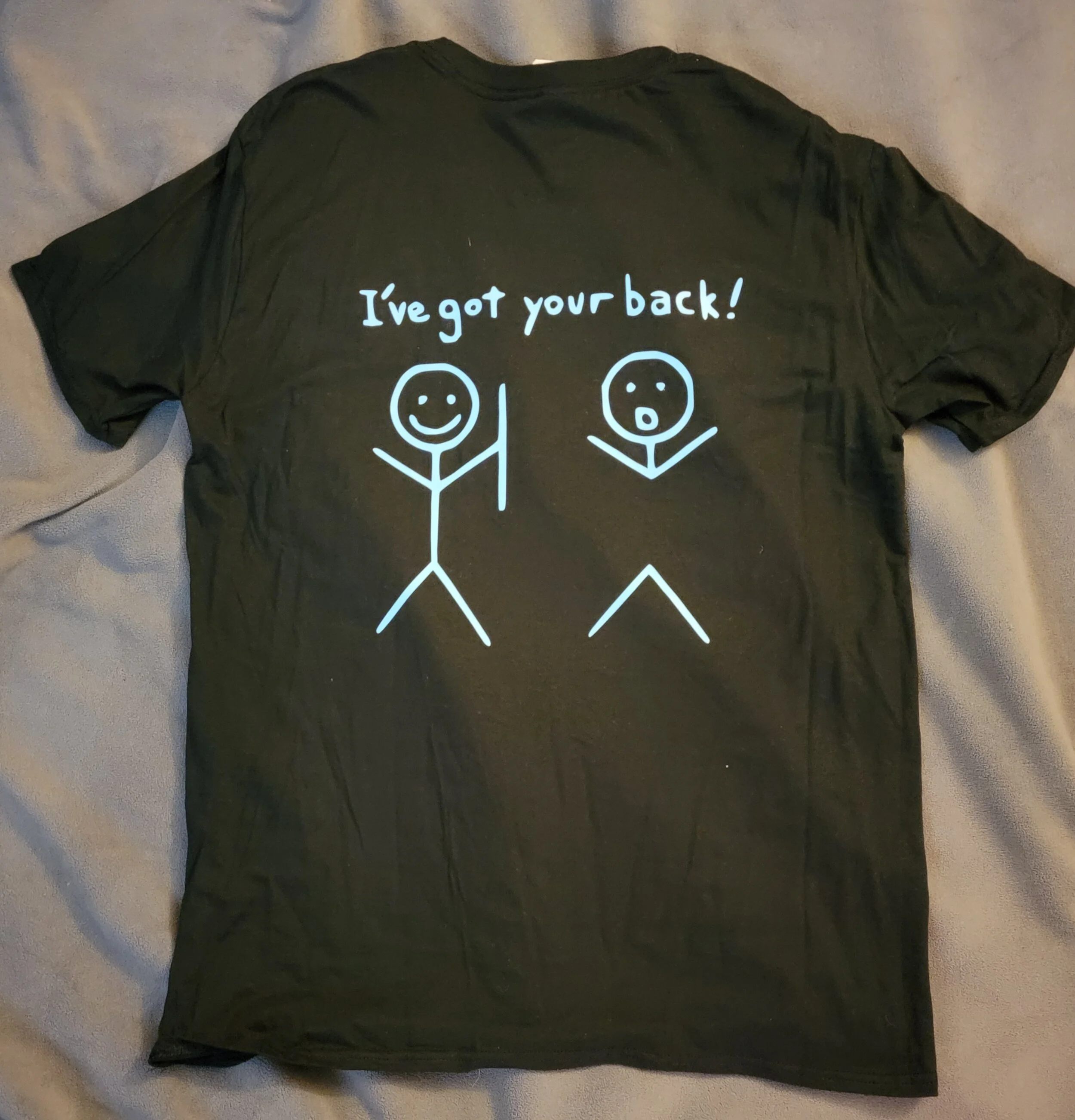 Black t-shirt with a white graphic of two stick figures; one smiling and holding a stick, the other surprised and with raised arms. The text above says, 'I've got your back!'