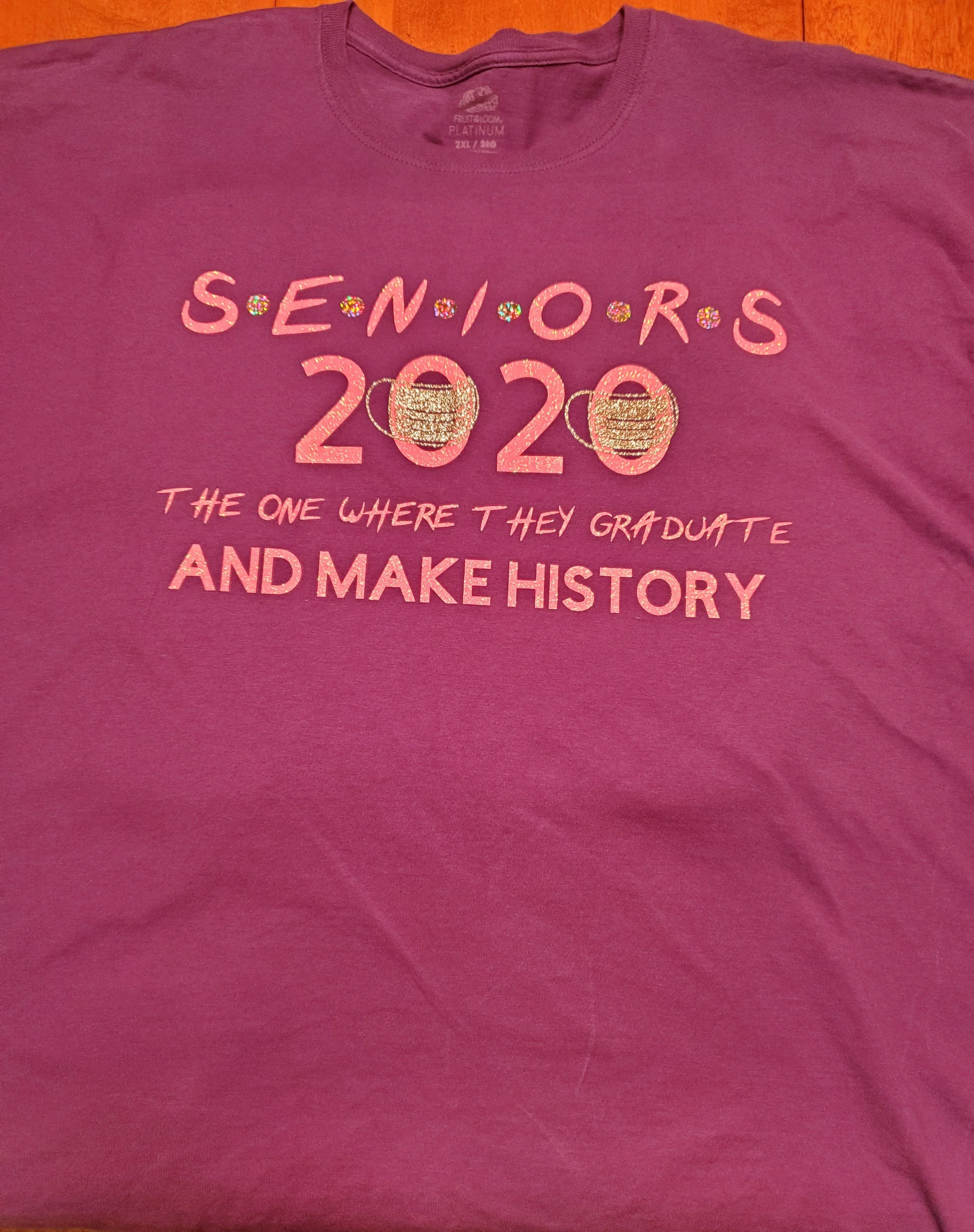 Pink T-shirt with shiny, glittery text and graphics celebrating the 2020 graduating class of seniors, with a phrase about making history.