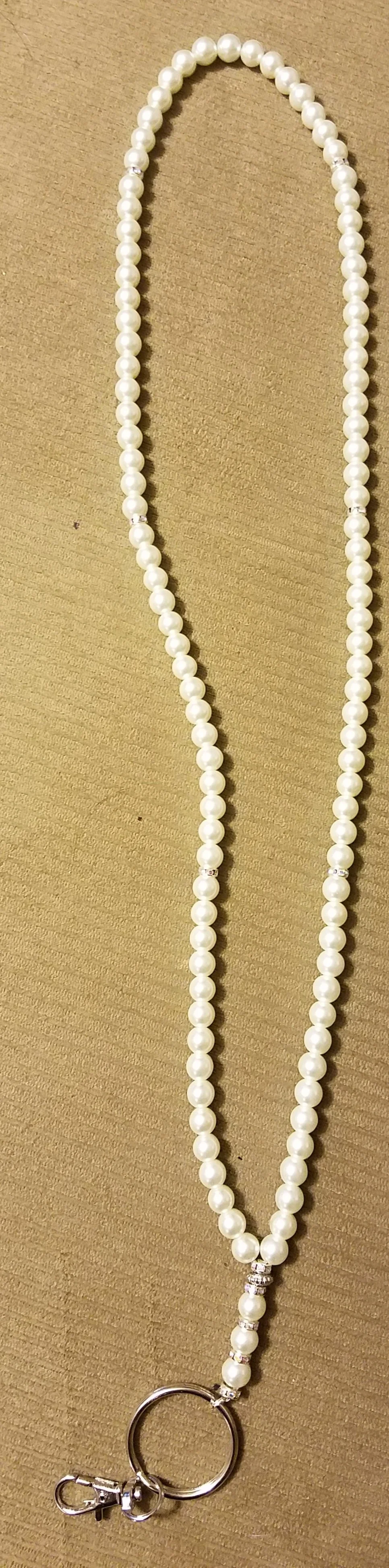 A pearl necklace with a silver clasp, lying on a wooden surface.