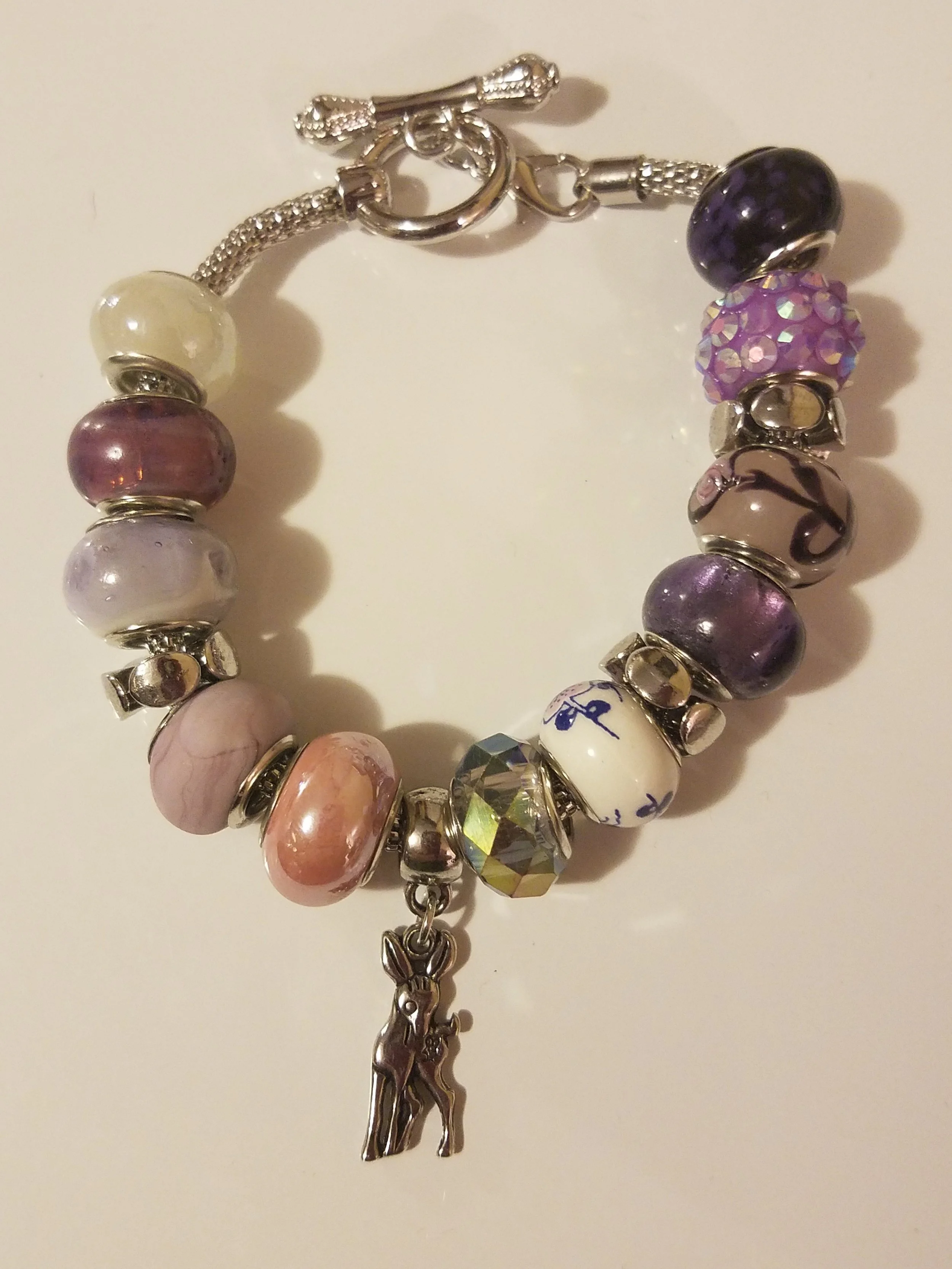 Colorful charm bracelet with various beads and a small dog charm hanging in the center.