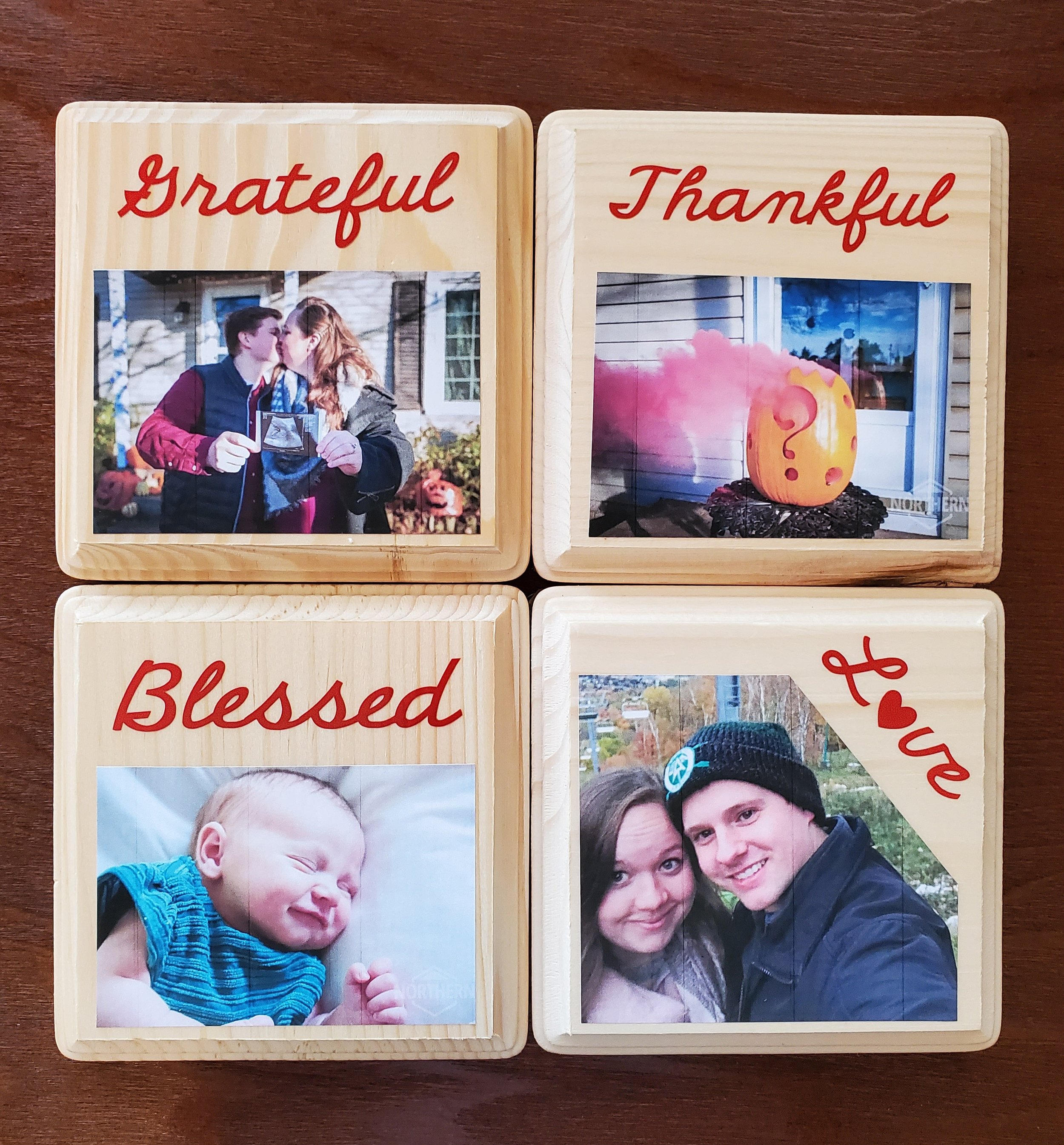 Four wooden photo blocks with images and words: 'Grateful' with a picture of a couple holding a sonogram, 'Thankful' with a pumpkin lantern, 'Blessed' with a smiling baby, and 'Love' with a couple smiling outdoors.