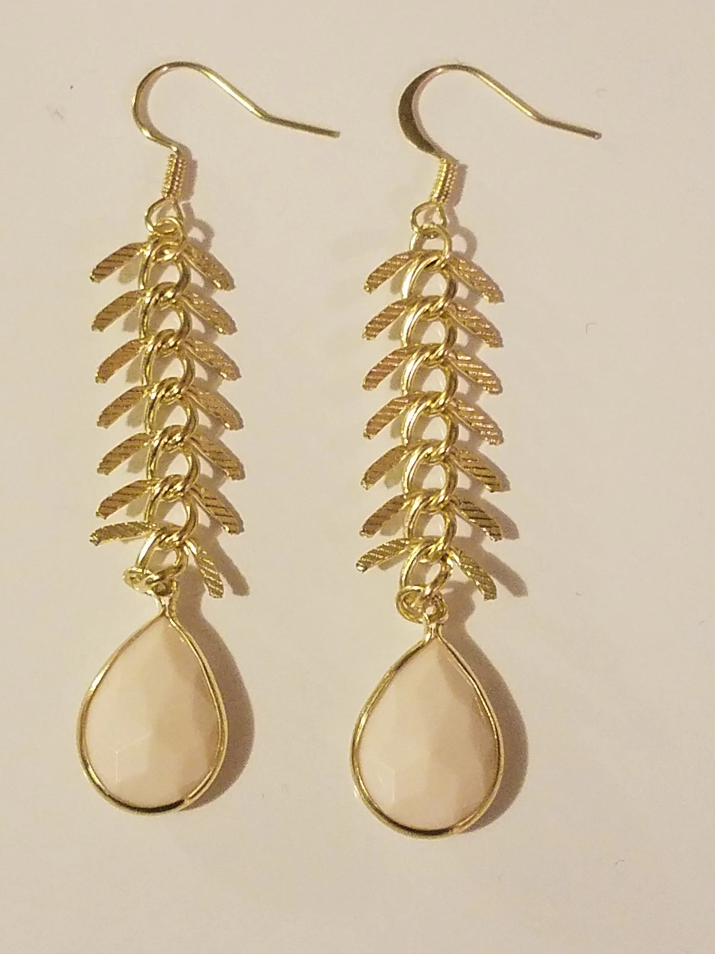 Gold dangling earrings with leaf and teardrop-shaped elements.