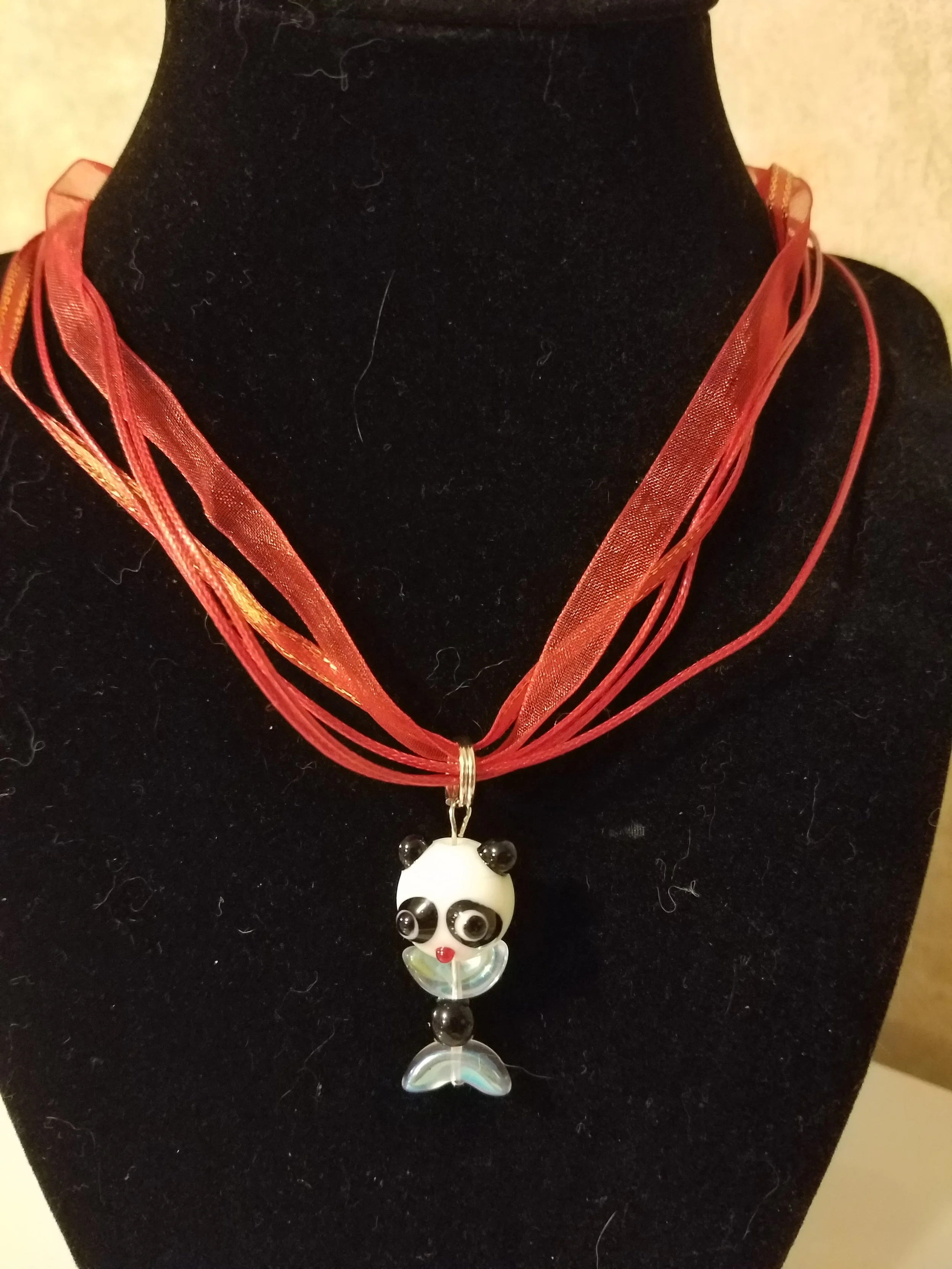 Necklace with a panda-shaped pendant on a black display bust.