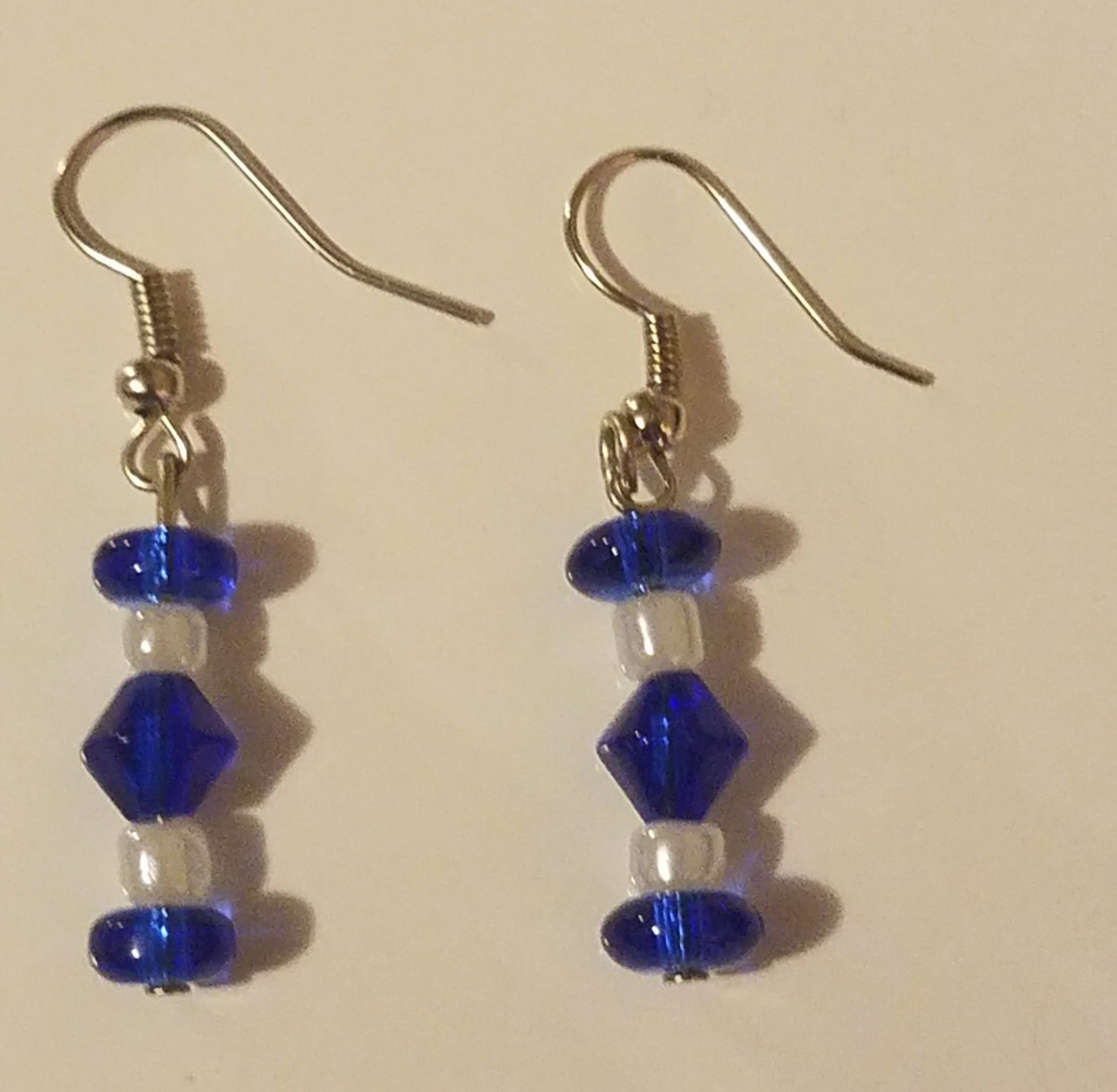 Silver earrings with blue and clear beads arranged in a vertical pattern.