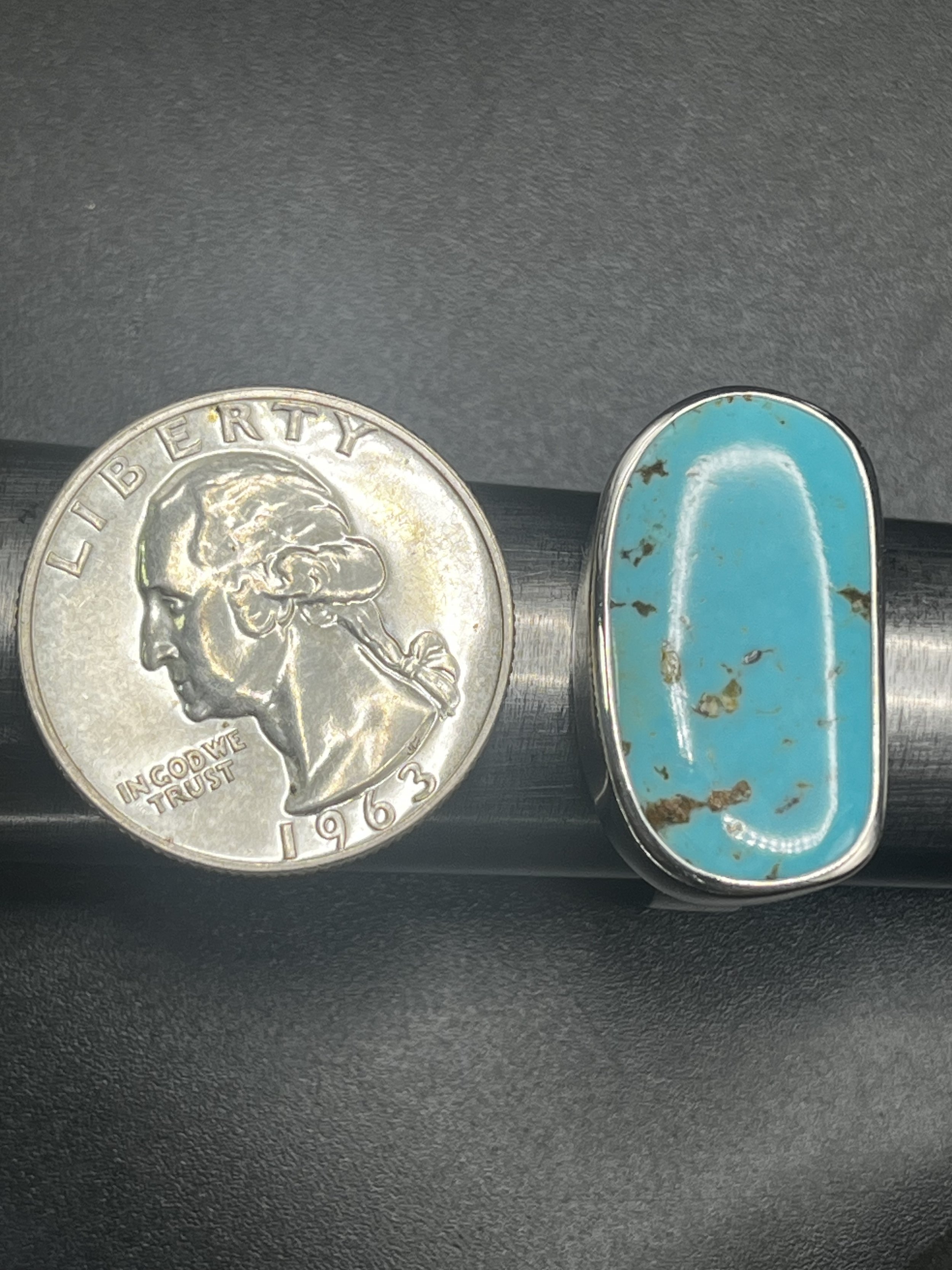 A turquoise gemstone next to a quarter.