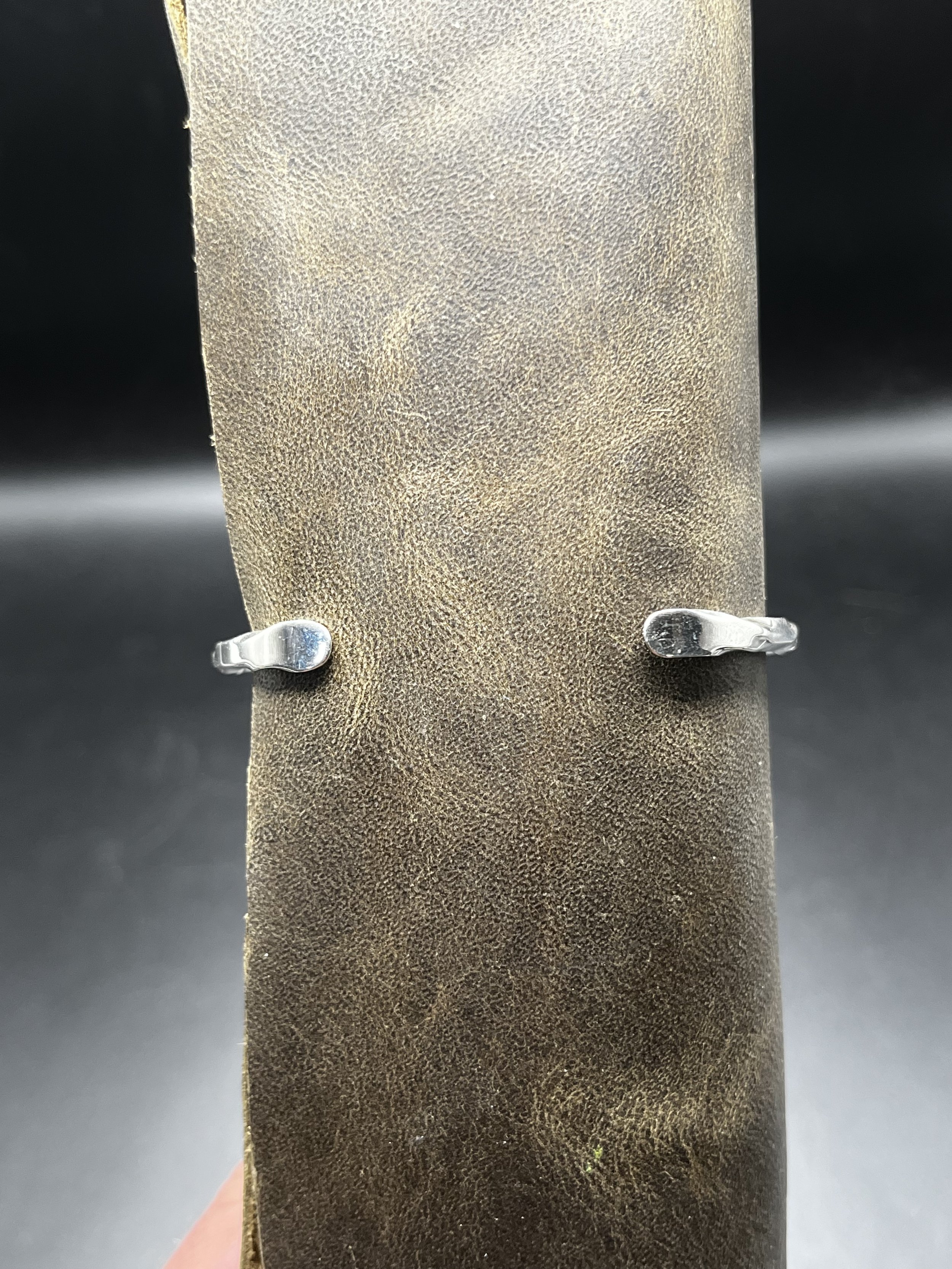 A bracelet with a twisted metal band displayed on a mannequin's arm. The bracelet is upside down to show the bottom of the sterling silver band.