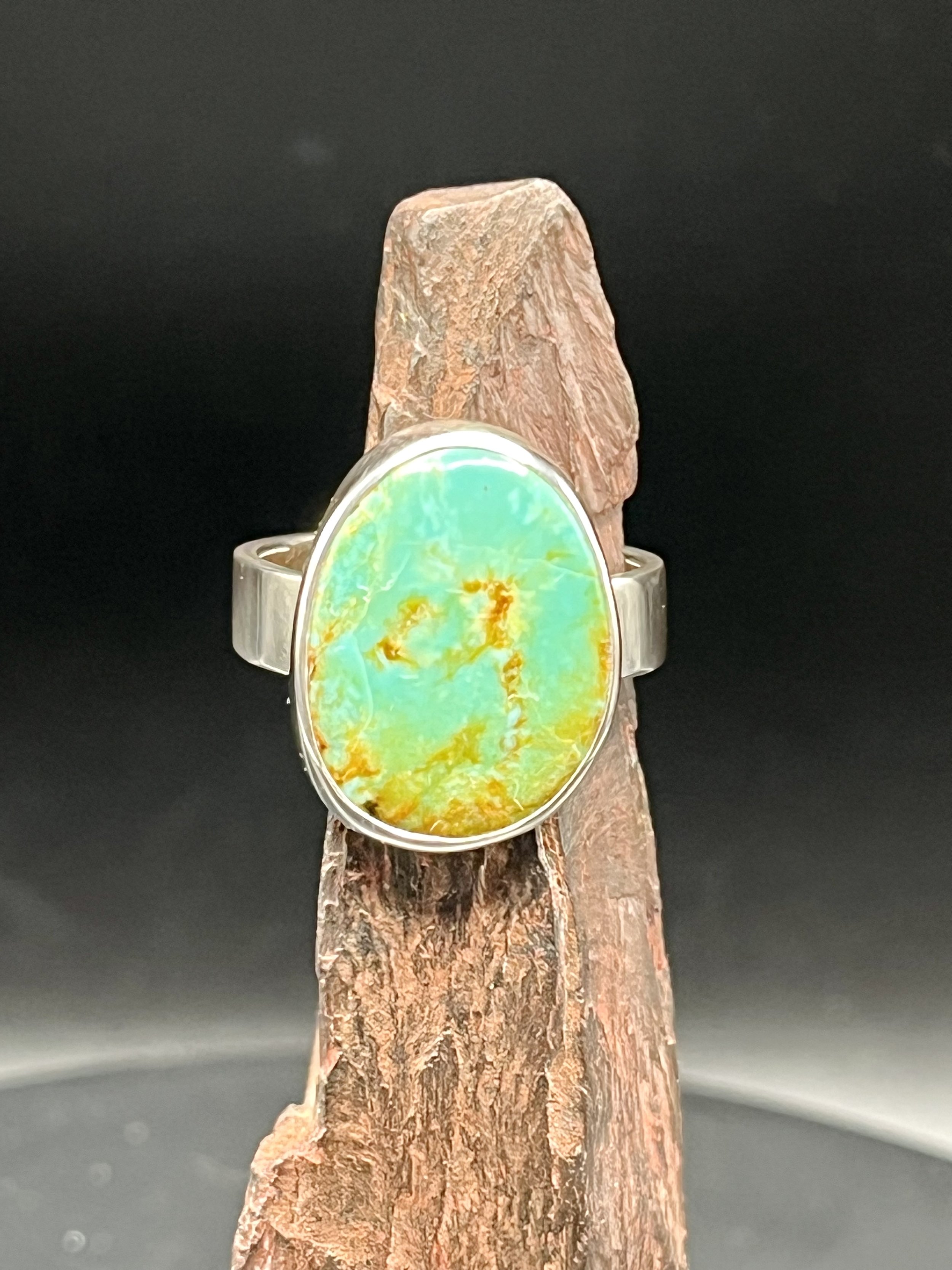 KC Silversmith's Kingman turquoise silver ring displayed on a jagged, rust-colored rock.