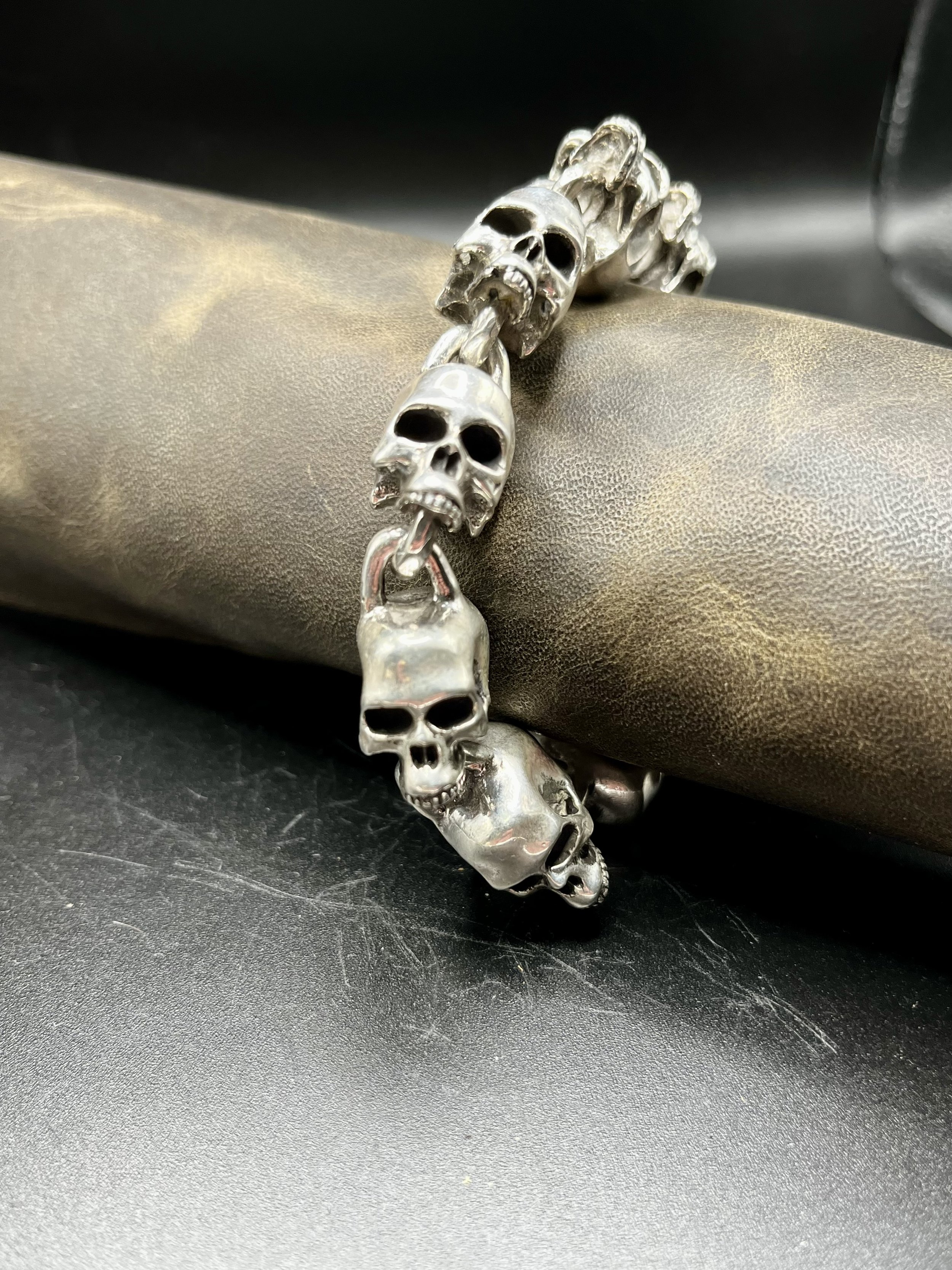 A bracelet of several hand-crafted skulls laid out on a mannequin arm.
