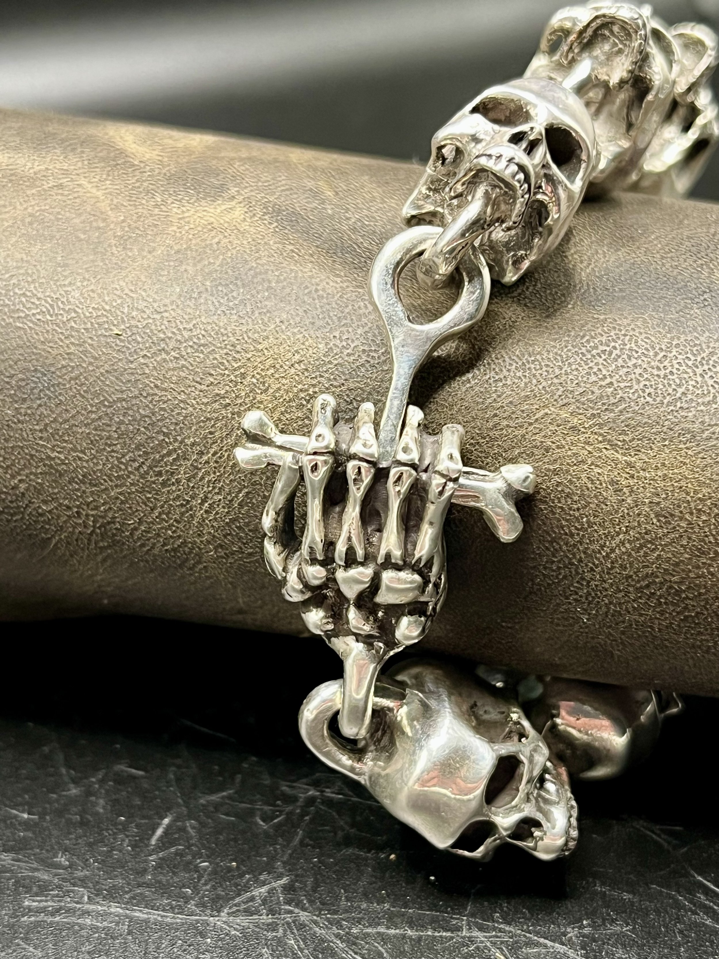 A bracelet of several hand-crafted skulls laid out on a mannequin arm.