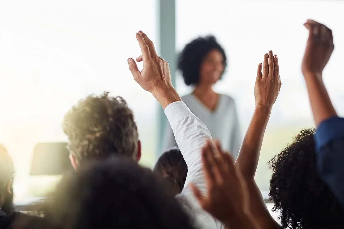 Audience raising hands at staff training workshop