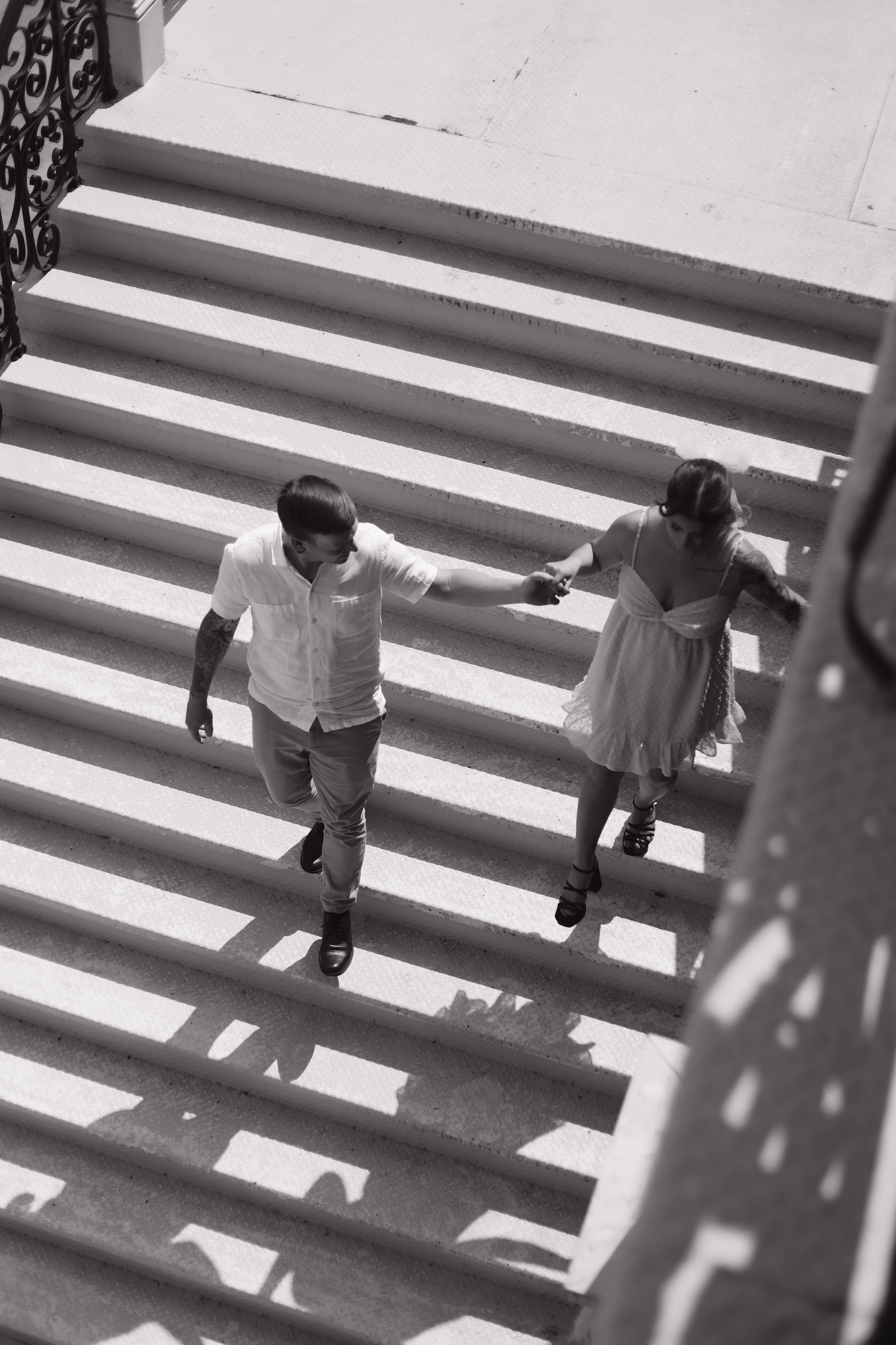 Black and white photo of a couple holding hands while walking upstairs
