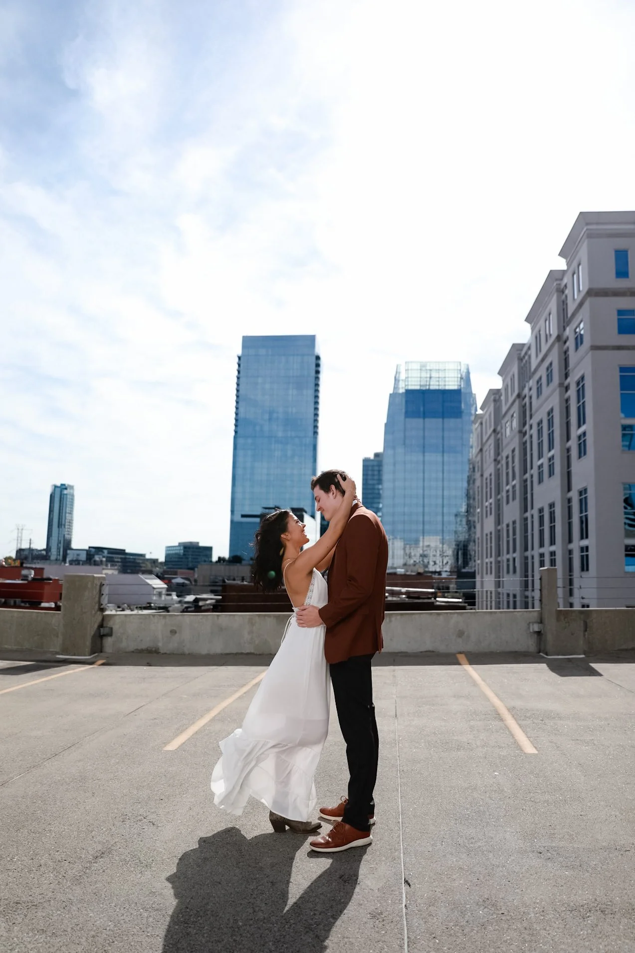A couple embracing on a rooftop with city buildings in the background.