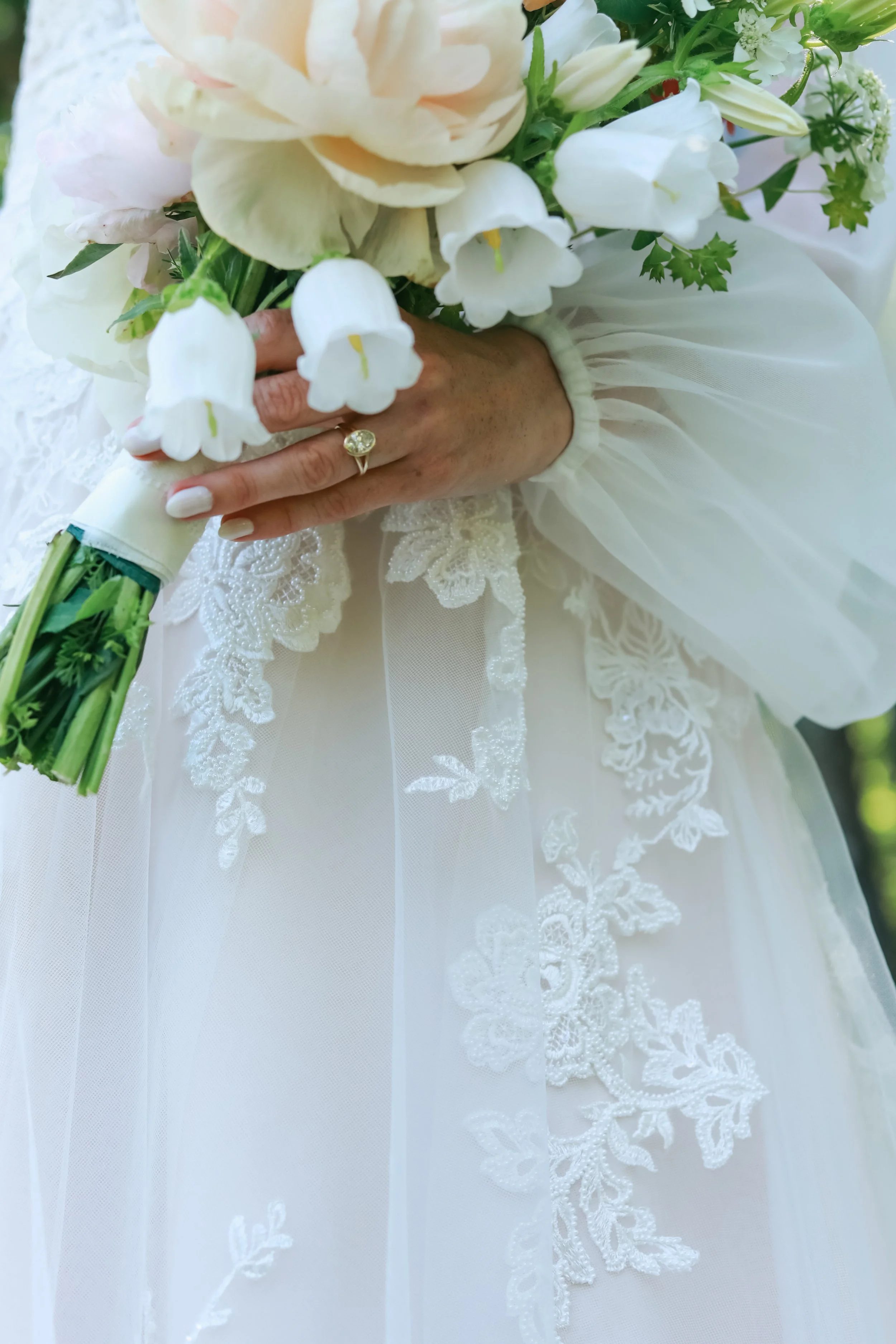 Bridal bouquet with white flowers and lace-detailed wedding dress.
