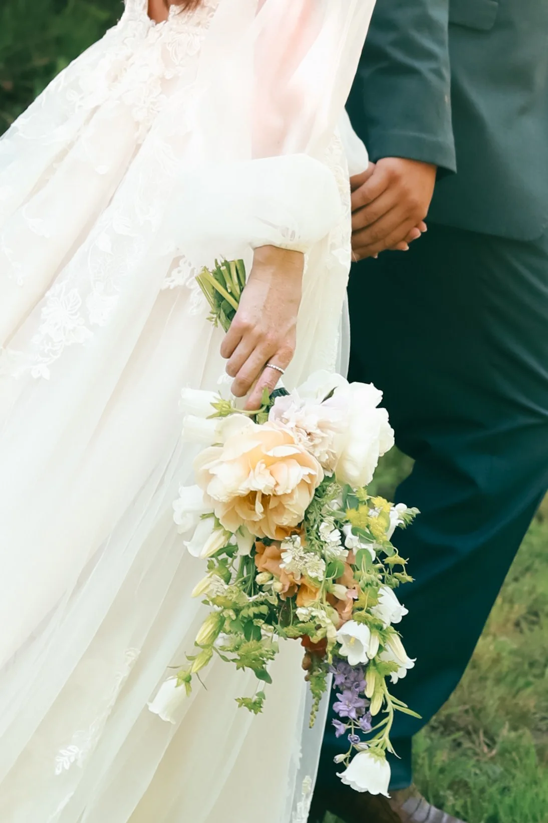 Bride holding bouquet with groom in the background
