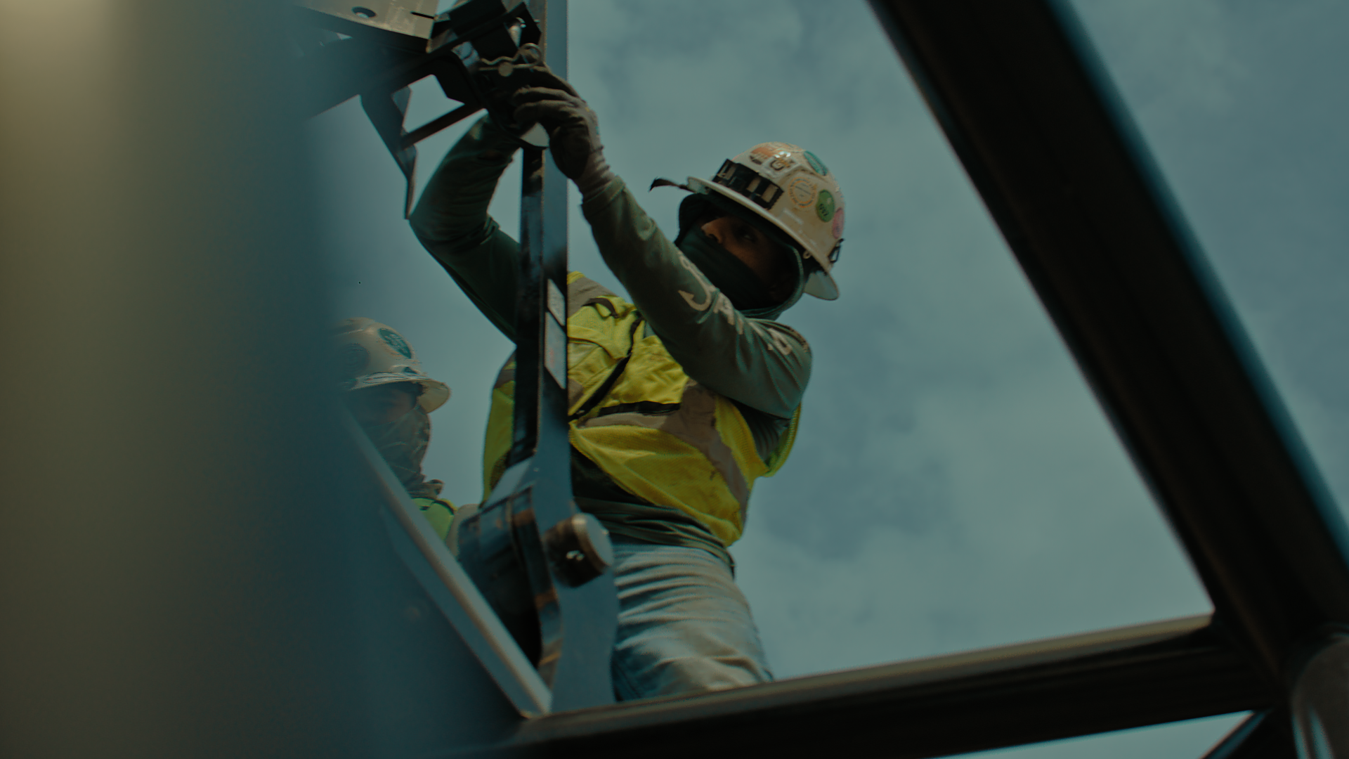 Utility worker in safety gear climbing a ladder above a roof hatch