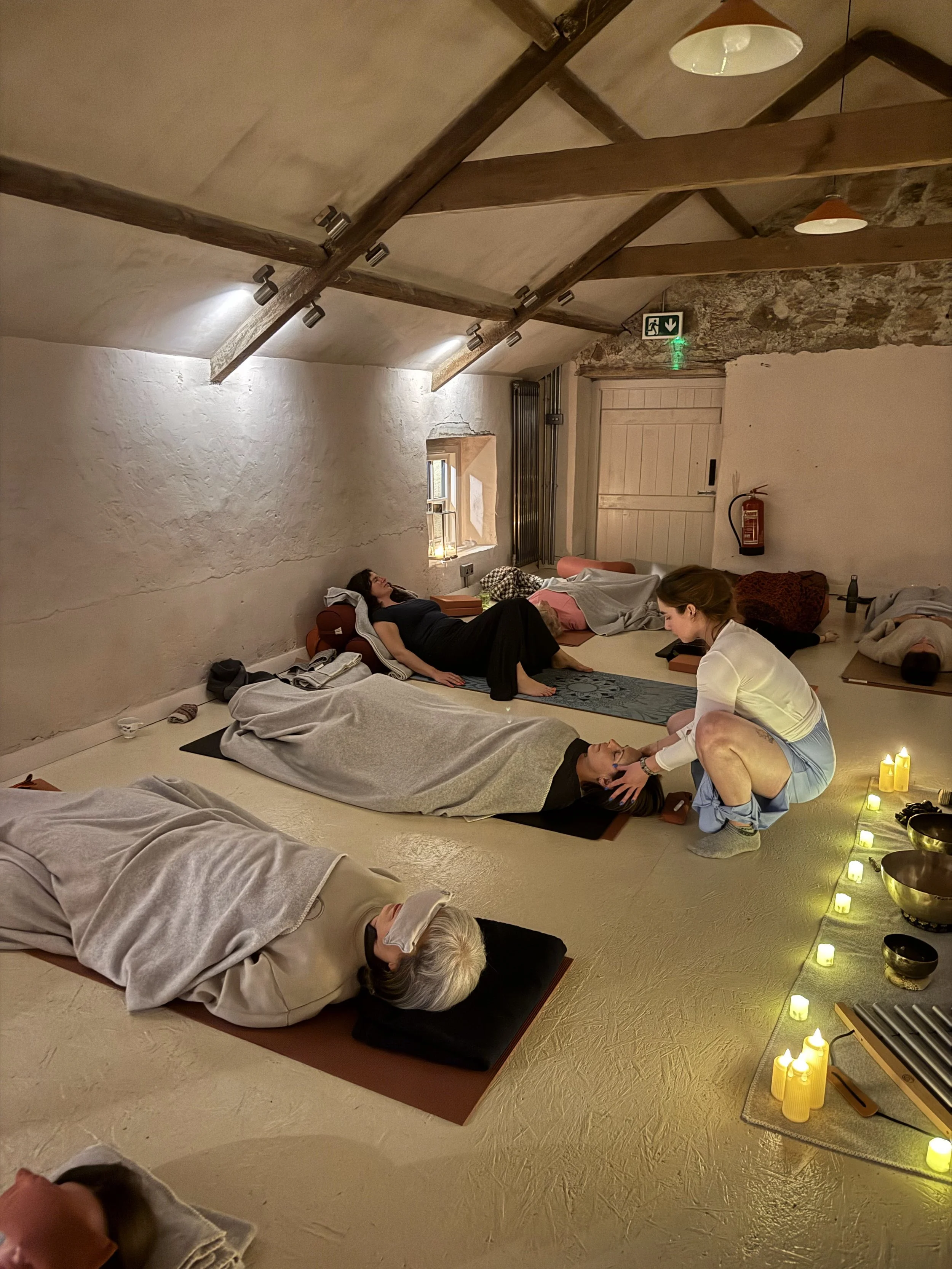 yoga teacher giving hands on savasana assist