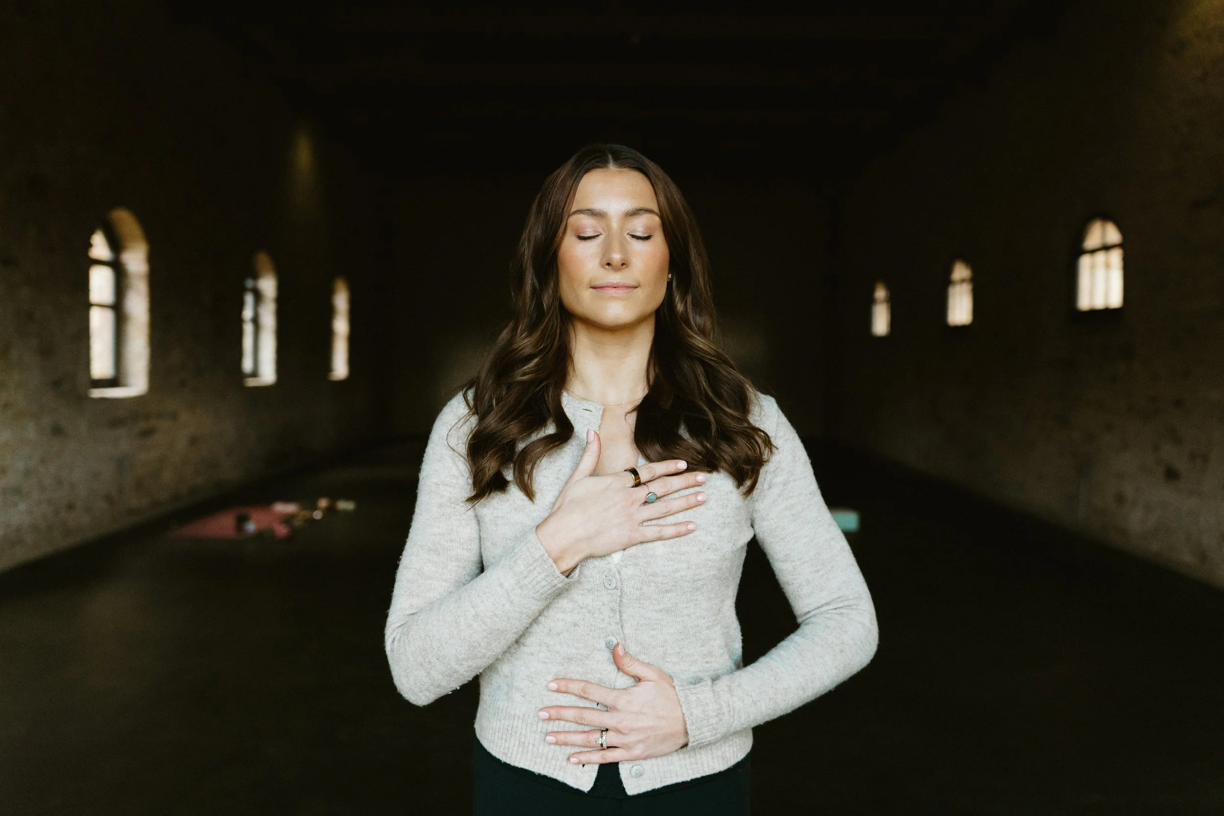 woman holding hands on heart and tummy in meditation