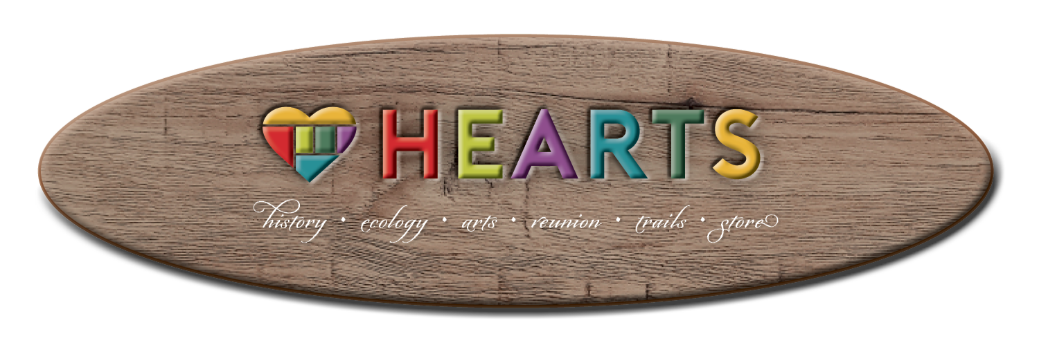 Wooden sign with multicolored text and a heart logo reading 'HEARTS'. Subtext includes 'history, ecology, arts, reunion, trails, store'.