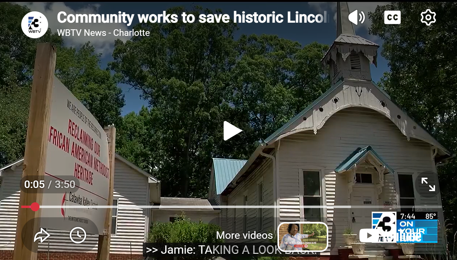 A small white historic church with a metal roof, surrounded by green trees. There is a large sign in front that reads, "We are people of faith, advocating for the reclaimer of our African American Methodist heritage." The image is part of a news report from WBTV Charlotte about community efforts to save the church.