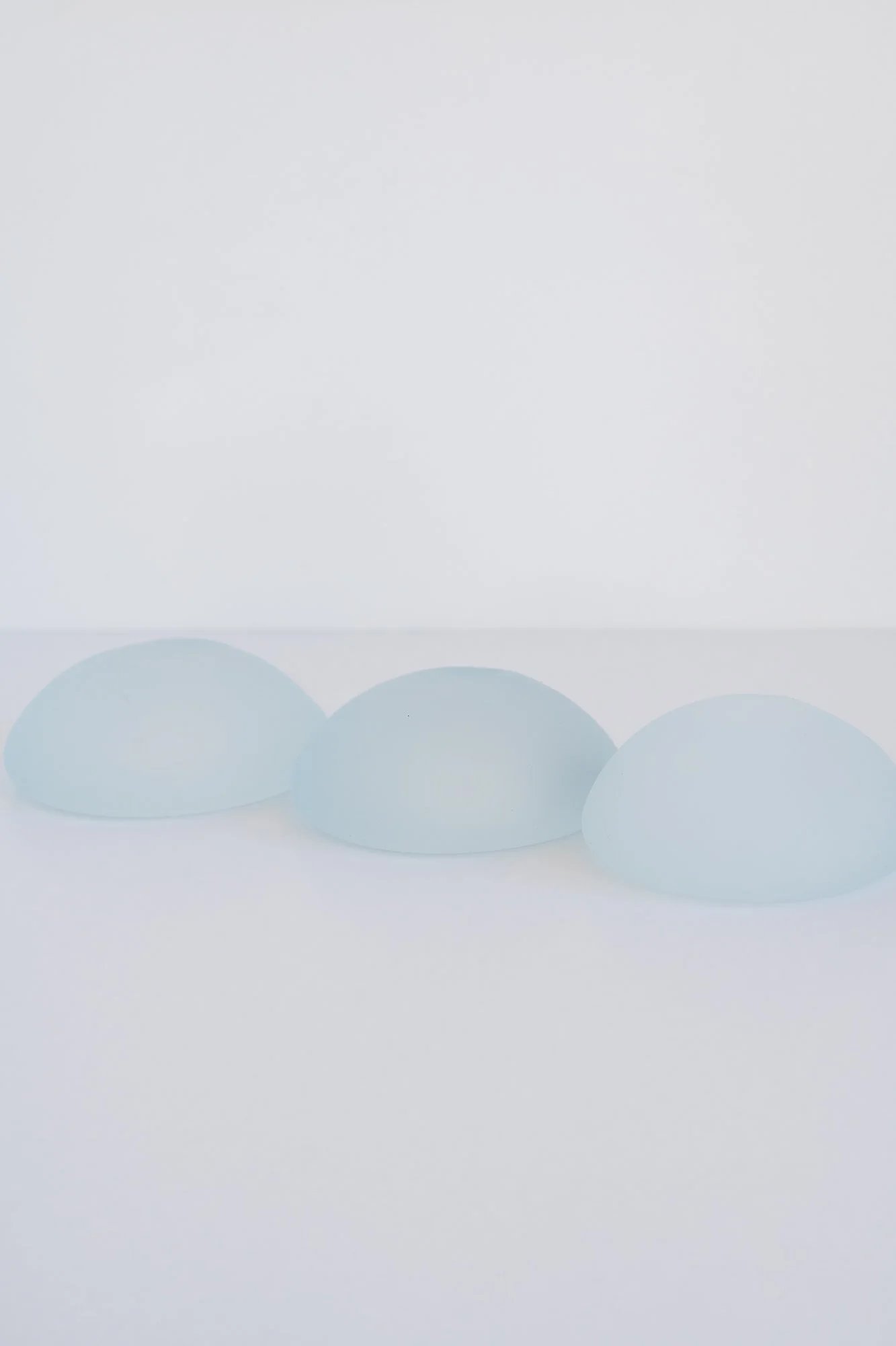 Three light blue eggs on a white surface with a white background.