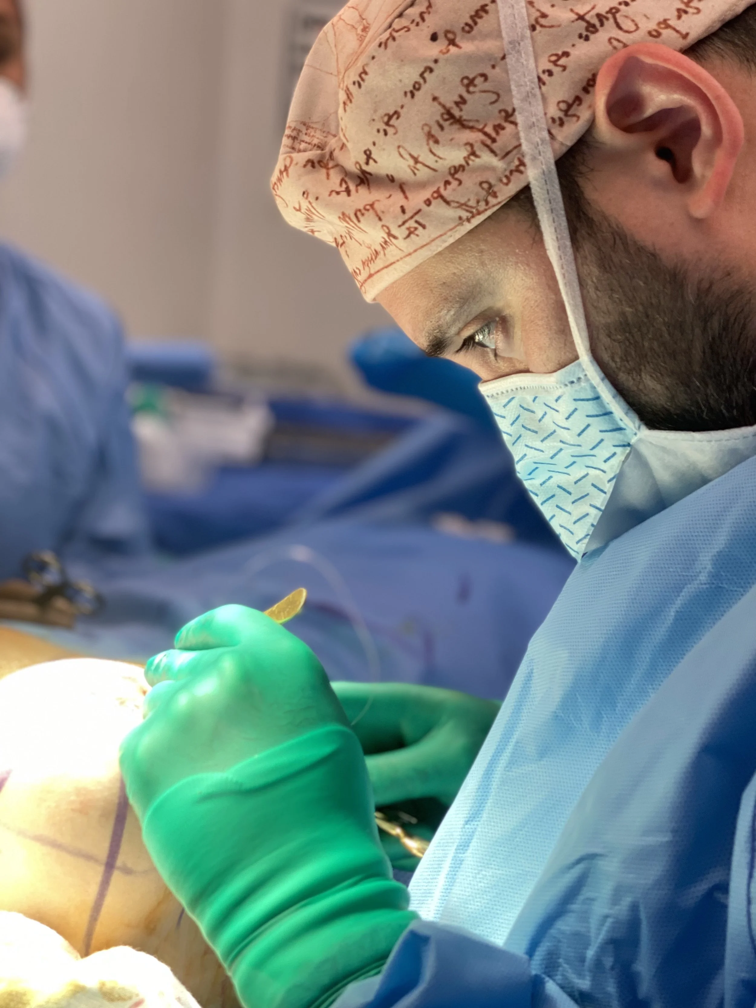 A surgeon wearing a surgical cap, mask, and gloves performing an operation in an operating room.