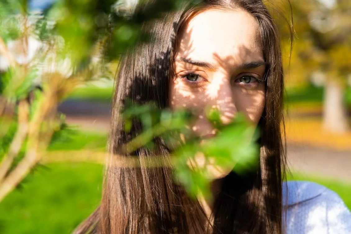 young-brunette-standing-behind-a-tree-branch