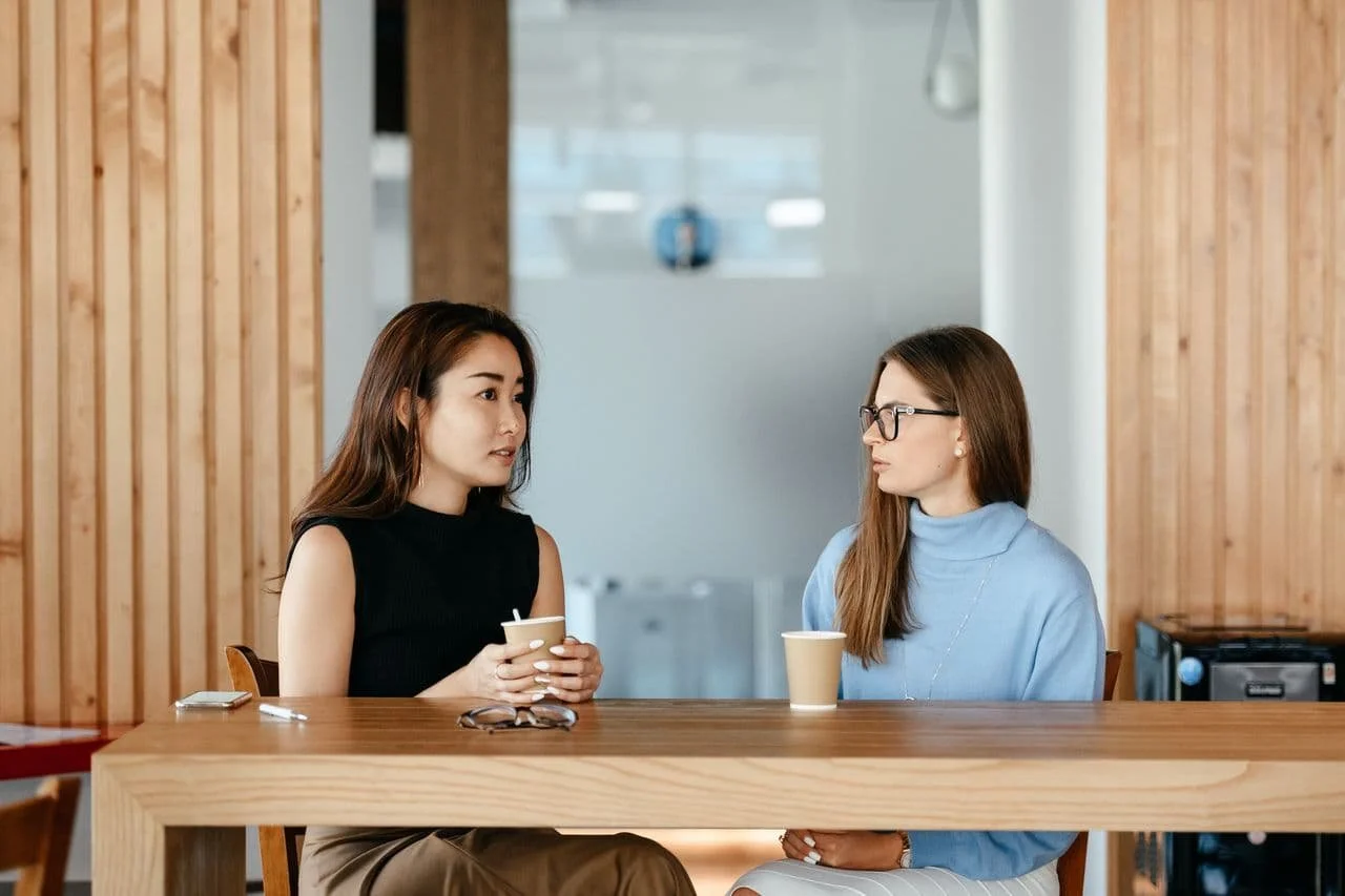 diverse-women-talking-during-coffee-break-at-table