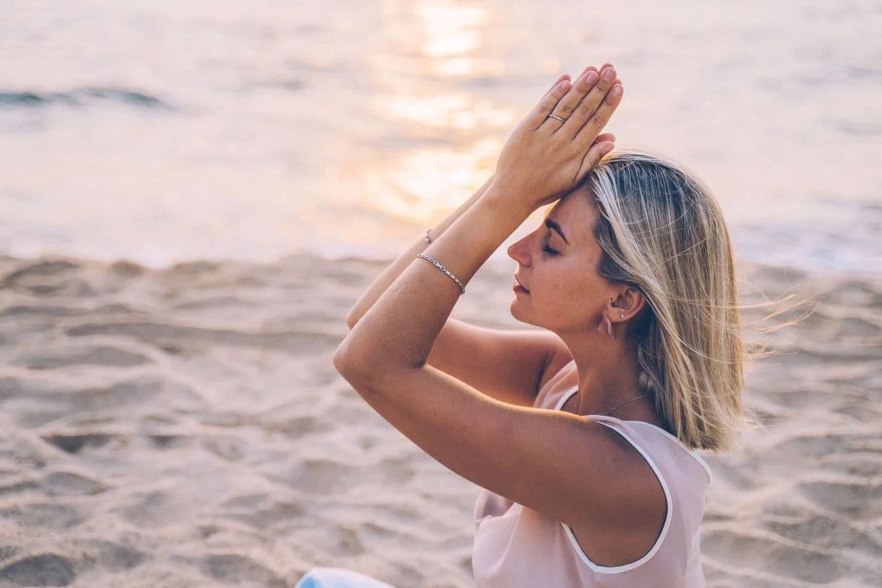 woman-sitting-on-the-beach-doing-yoga