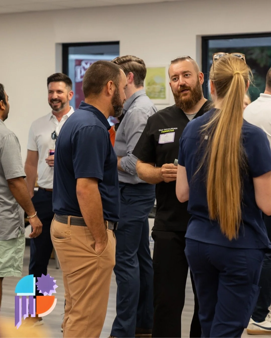 Group of professionals having a conversation at a networking event in an office setting.