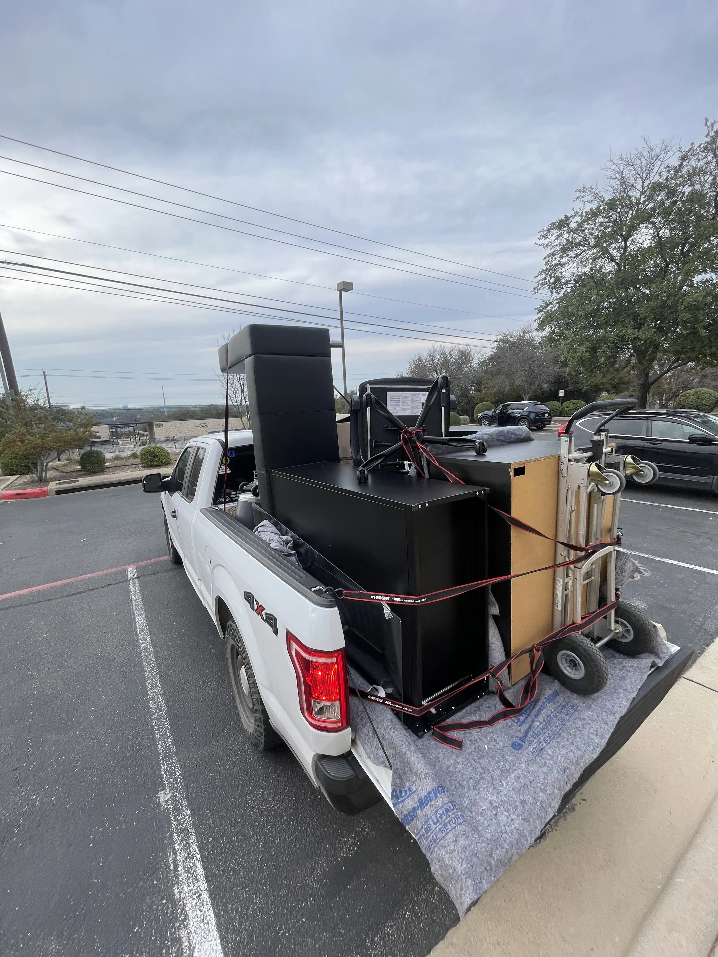 alt="office furniture moving cleaning out pickup truck moving desk couch file cabinet dolly secured strapped in"