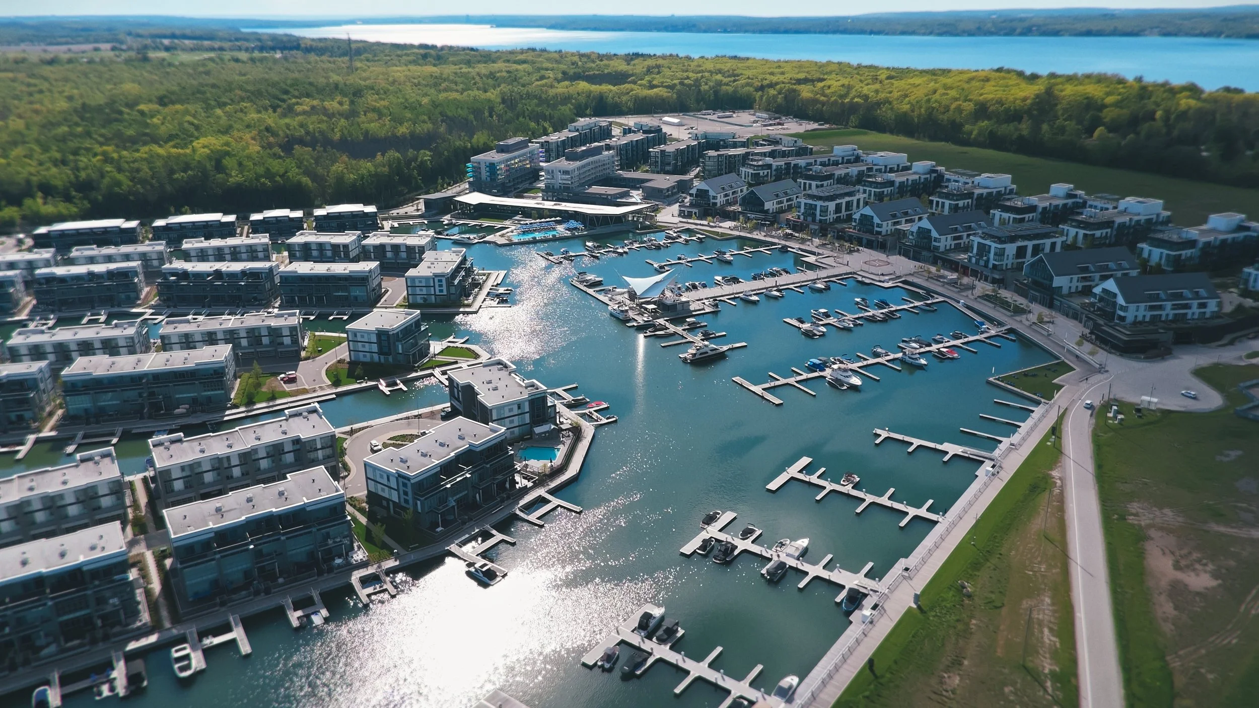 Aerial view of a marina with boats docked in calm water, modern residential buildings nearby, it's an example image of a drone shot of the Friday Harbour Resort