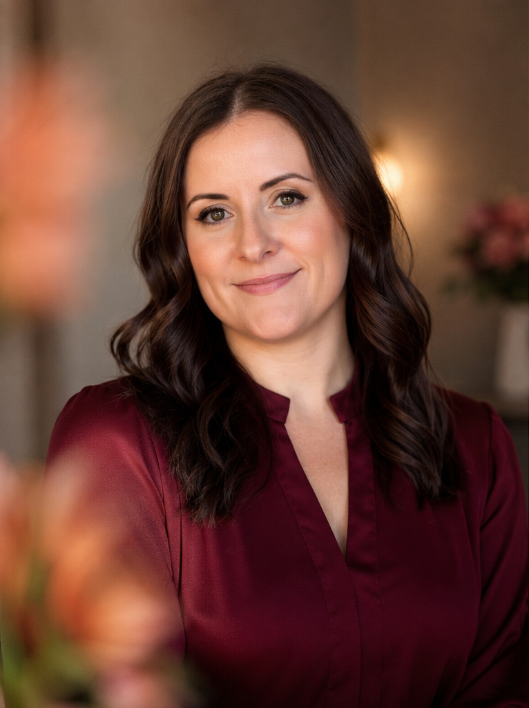 Erin Wilson, smiling in a warmly lit room, wearing a deep red blouse.