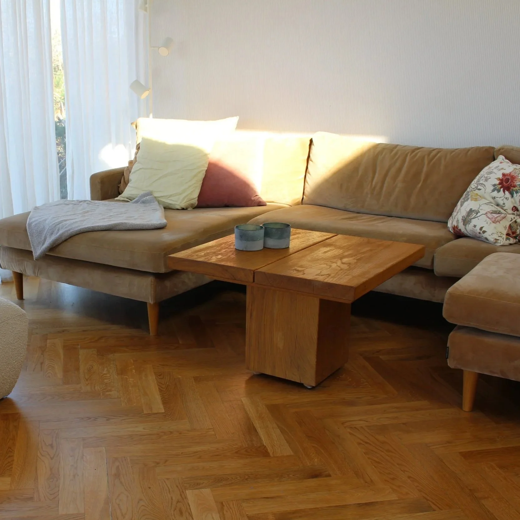 Lavt sofabord i massivt egetræ fra BUK Studio i varm stue med sofa og sildebensparket