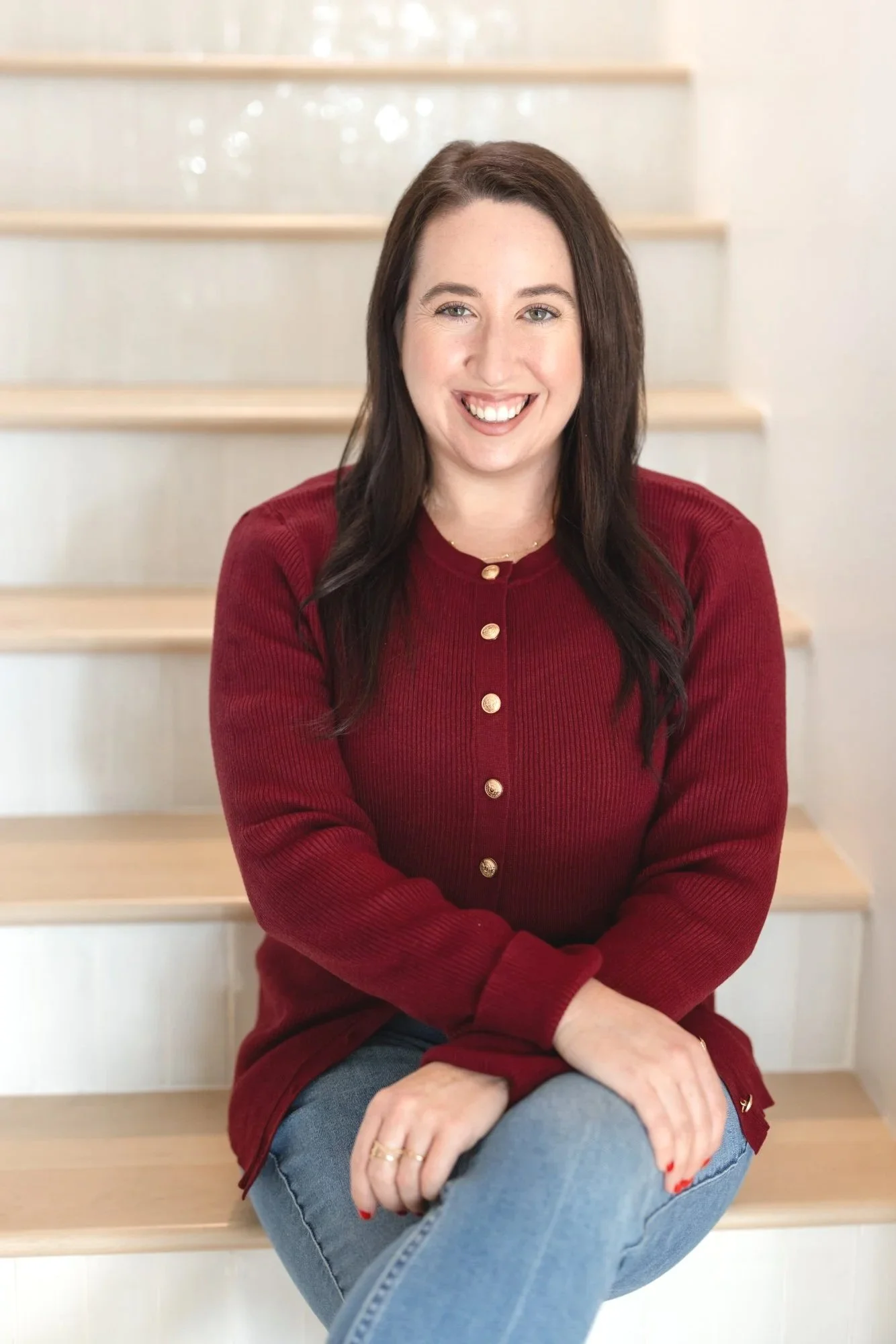 Licensed Therapist Alexa Levine at her home therapy office in San Diego, CA wearing a red sweater and jeans.